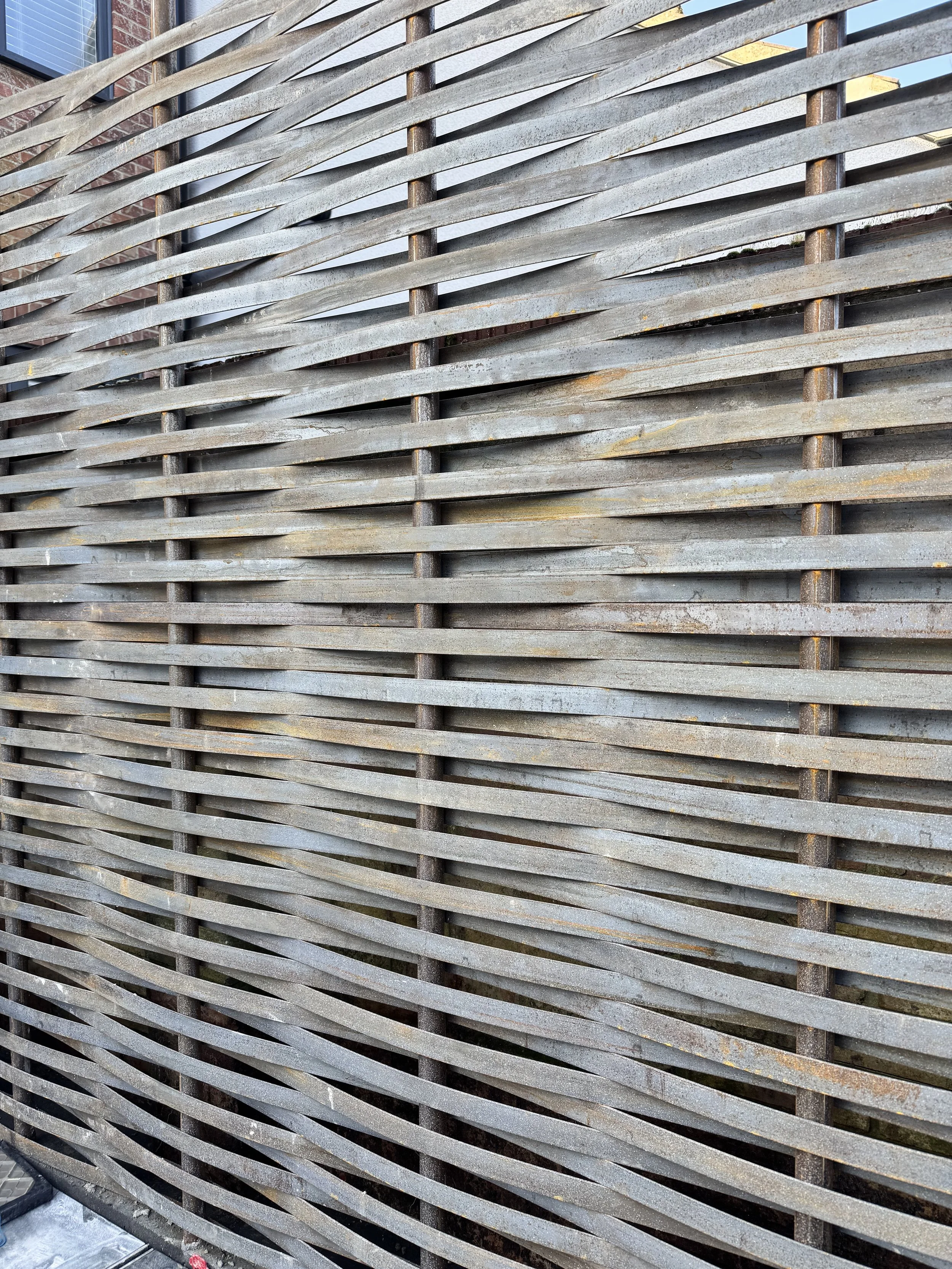 Close-up of a weathered wooden slatted fence with horizontal slats and rusty metal supports.