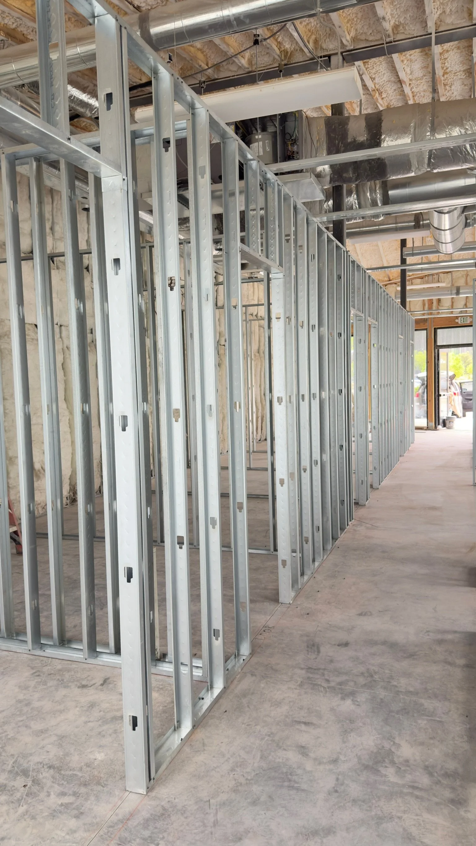 Construction site with metal framing for walls and exposed ceiling ducts.