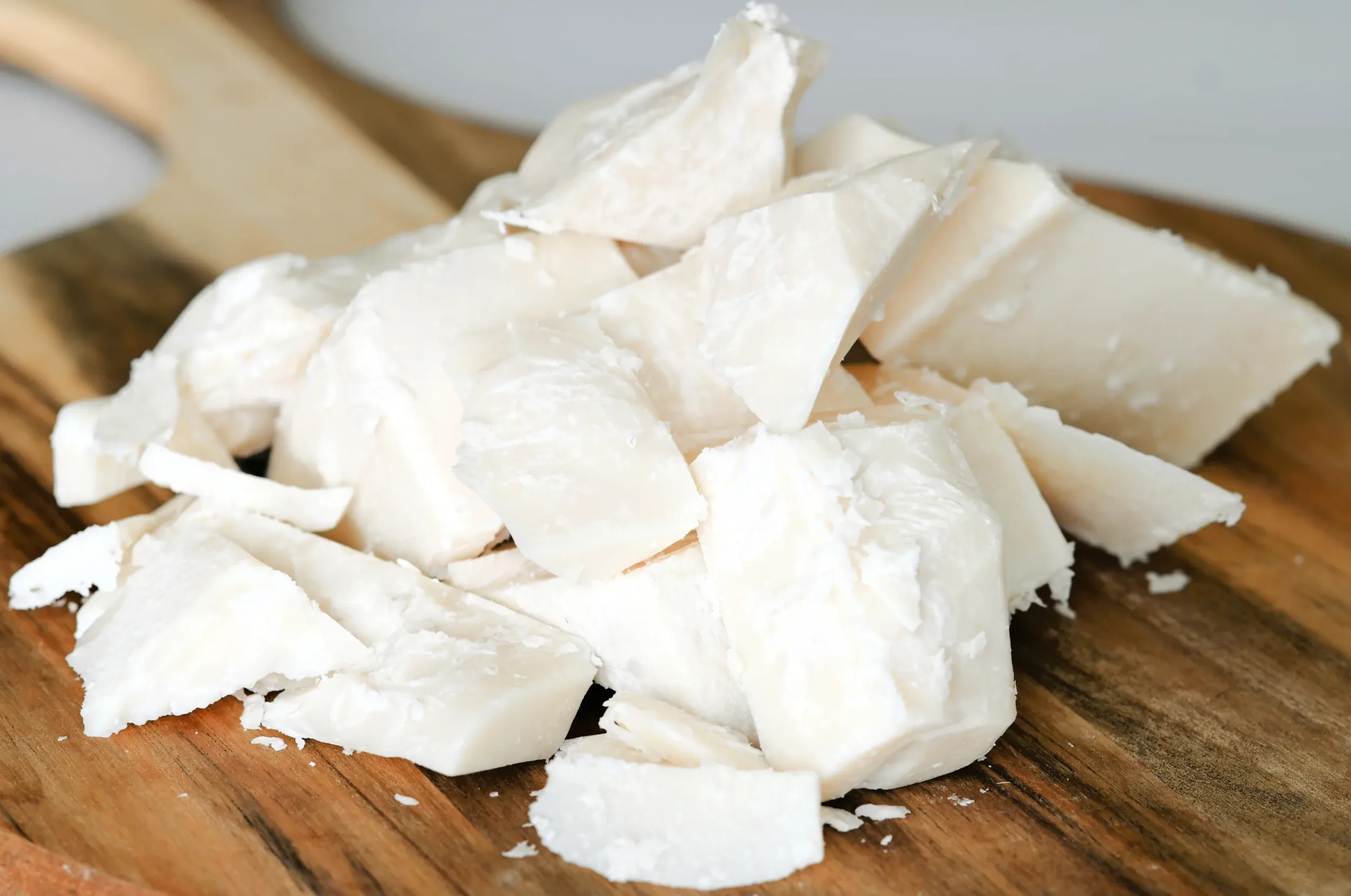 Grass-fed tallow, cut into chunks, on a wooden cutting board.
