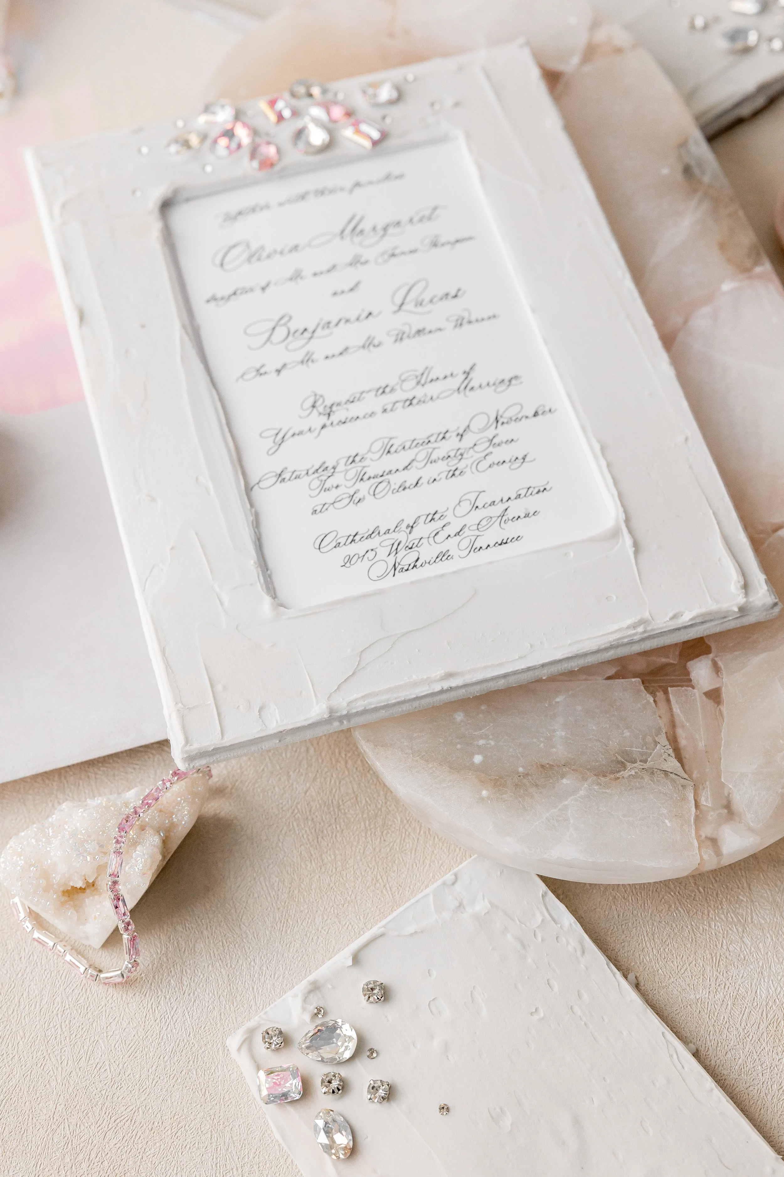 A softer blush accent on the stones creates a subtle, heirloom feel, perfectly complementing the full invitation suite.
