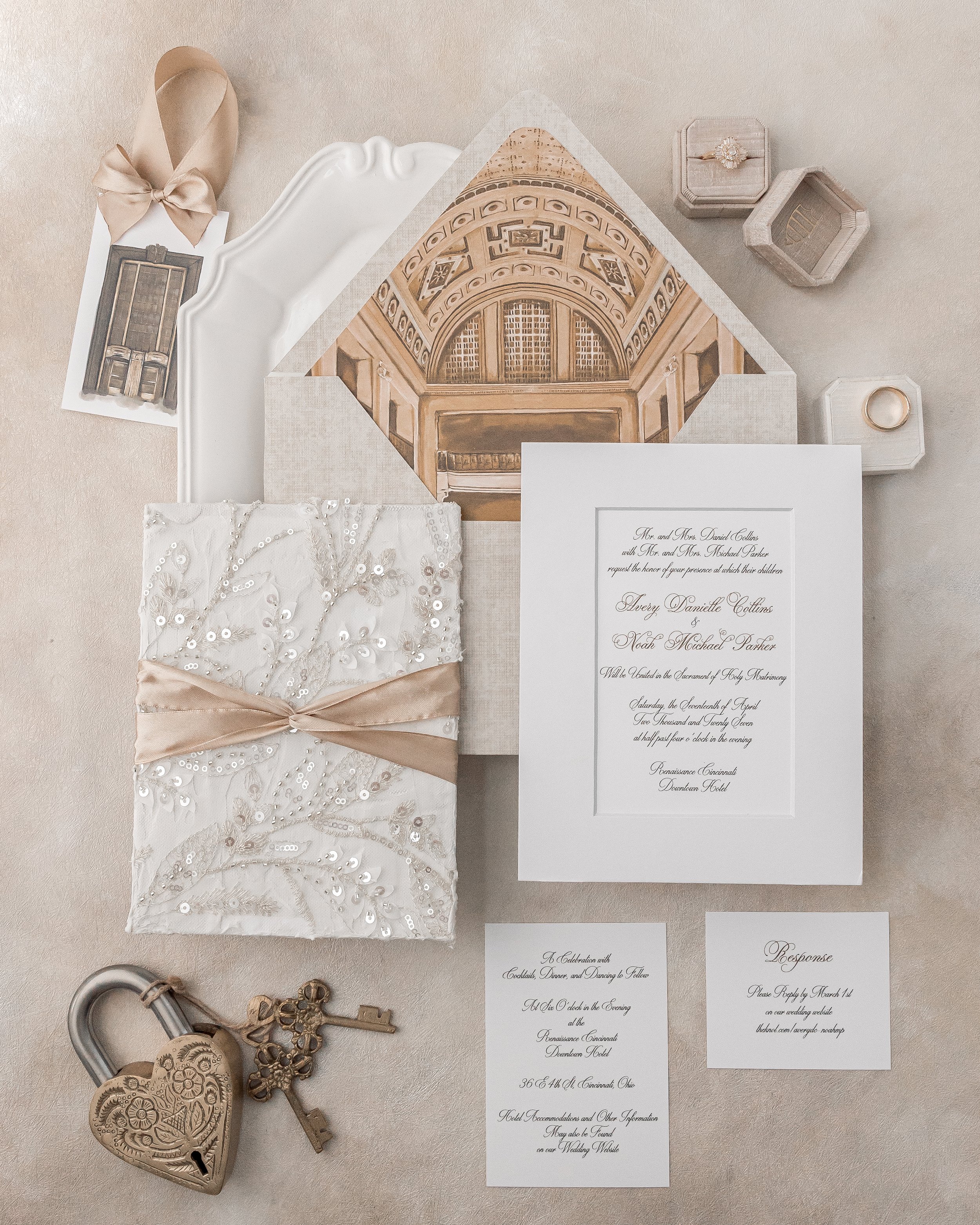 Fully digital printing in elegant script is paired with dimensional textures, gold satin ribbon ties, and a custom hand-painted and digitized vinyl envelope liner depicting the Renaissance Cincinnati Downtown. Coordinating response cards, celebration