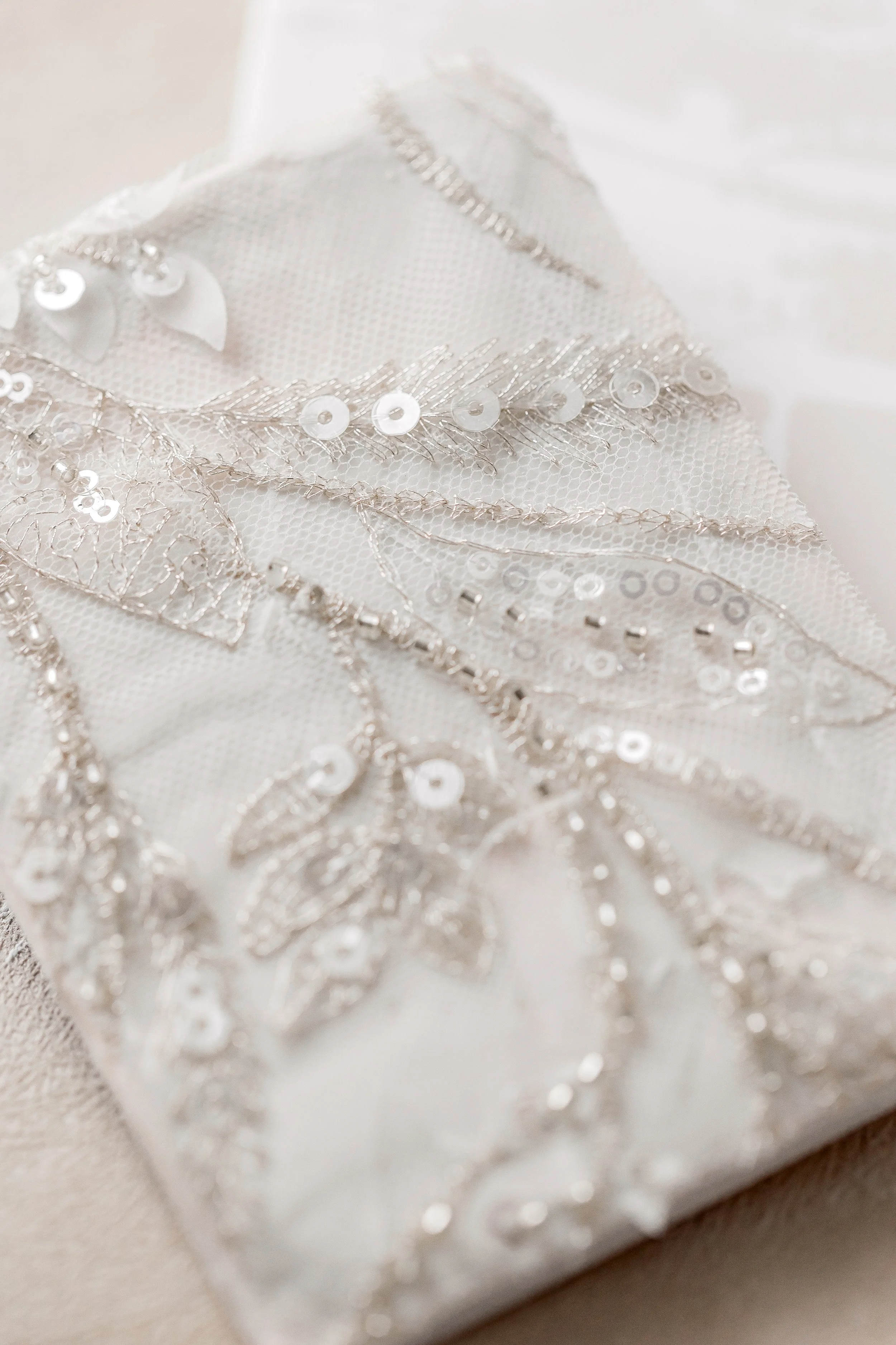 A close study of the hand-applied fabrid with sequins, champagne beading, embroidered threads, and layered ribbon; each element intentionally placed to reflect light and add depth to the textile surface.