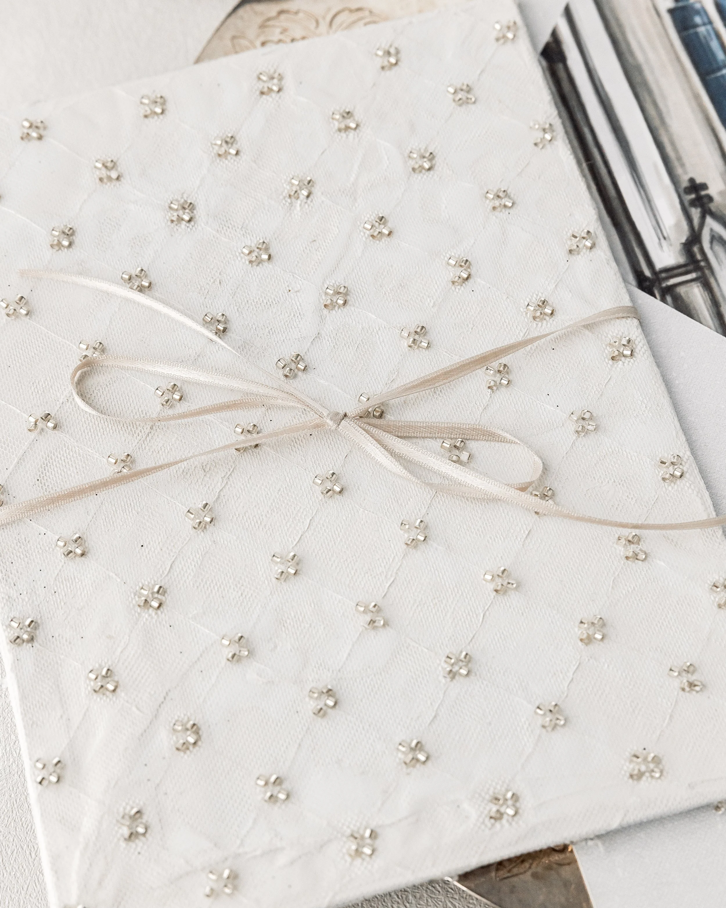 A thin, double-sided satin pearl-champagne ribbon ties the suite together with subtle sculptural elegance.