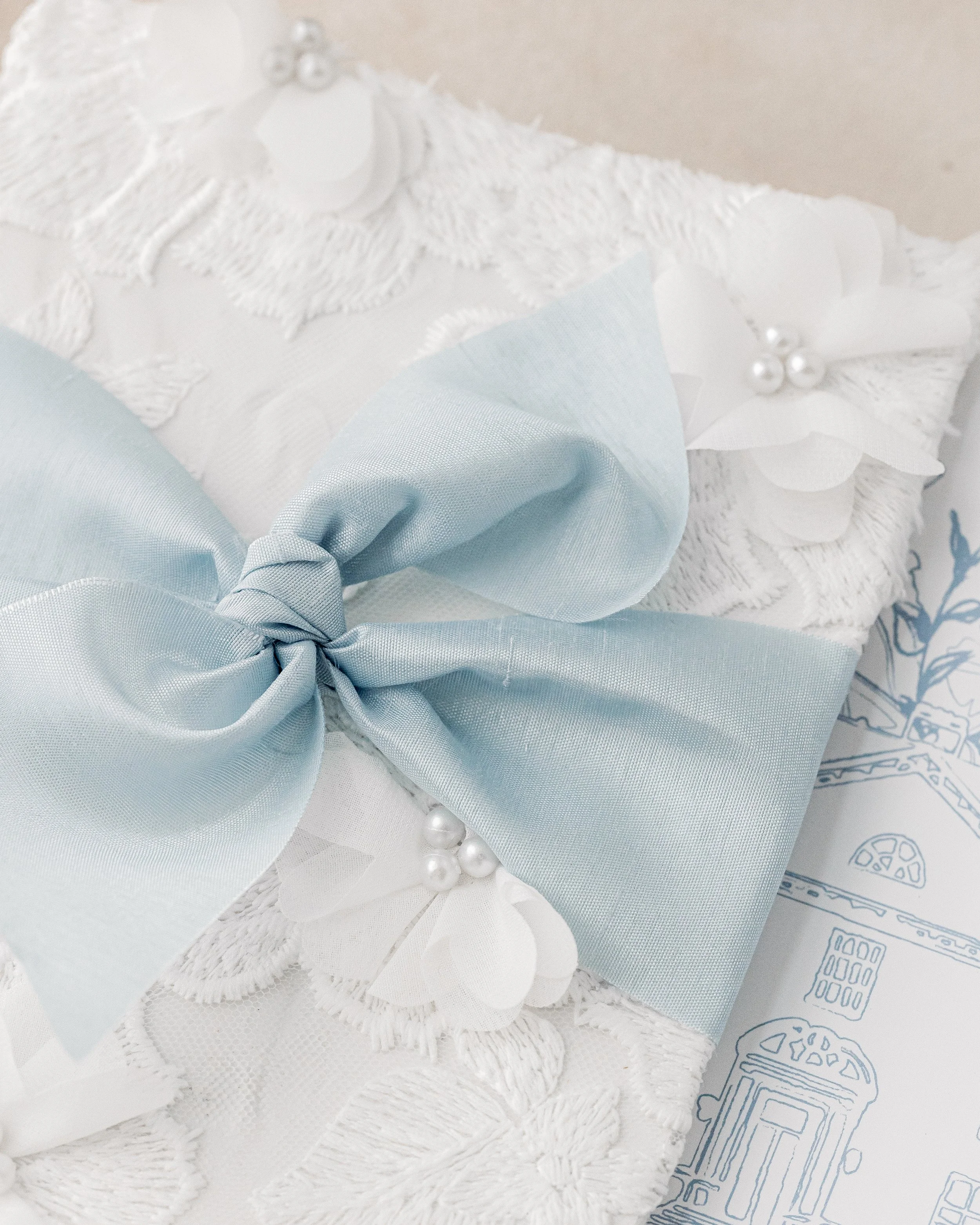 Covered in NOTE’s signature textured fabric with pearl embellishments and subtle 3D floral elements, creating a tactile, heirloom-quality experience
