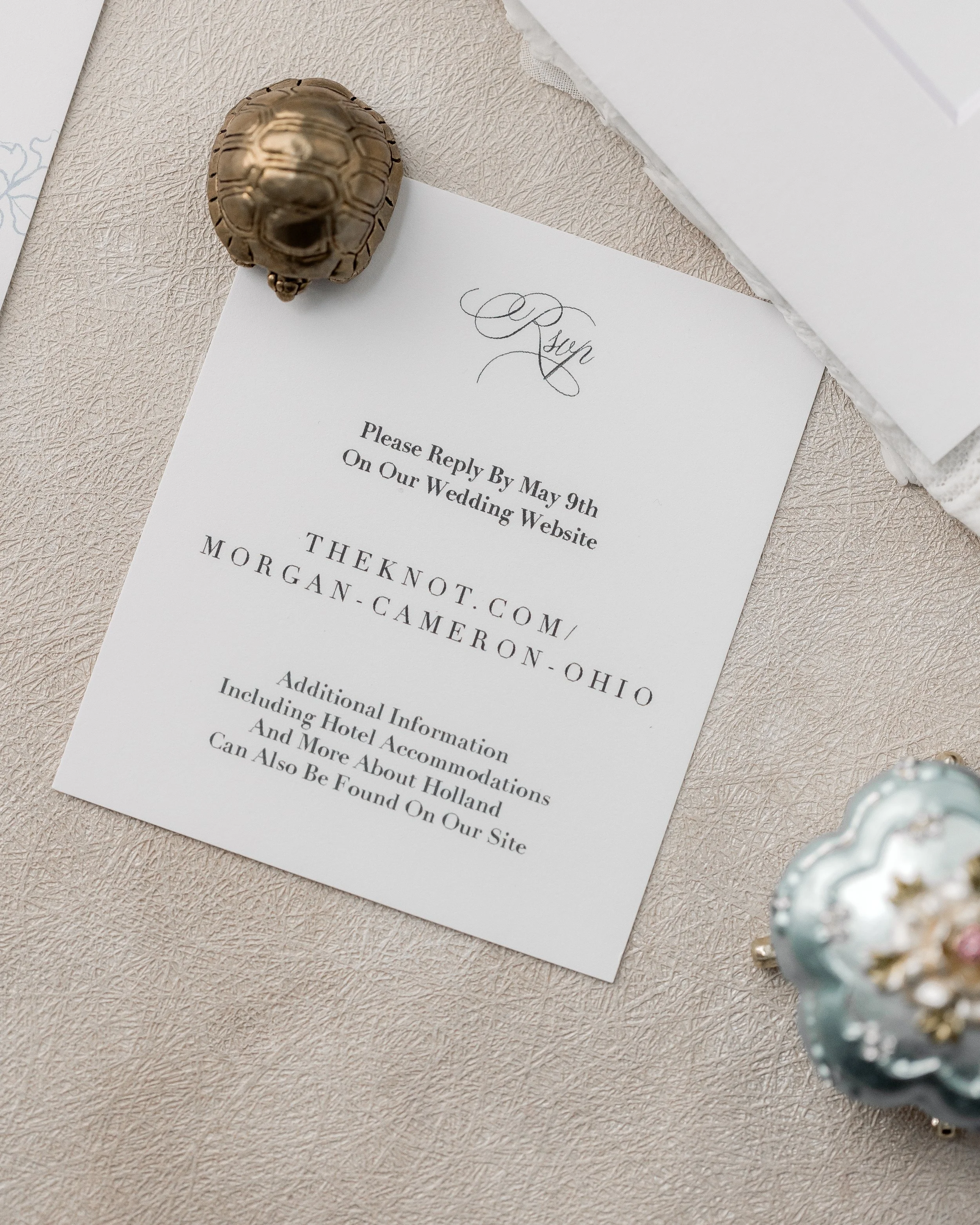 The RSVP enclosure mirrors the suite’s elegance, with matte layers, script typography, and understated dimensional embellishments that make each response feel intentional.