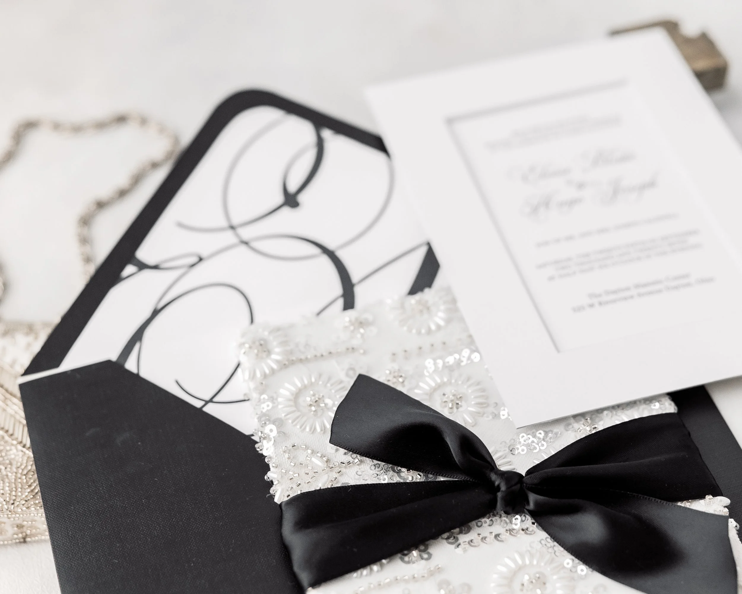 The mounted vinyl liner glimmers softly within the solid black envelope, reflecting light and anchoring the invitation’s luxurious monochrome story.