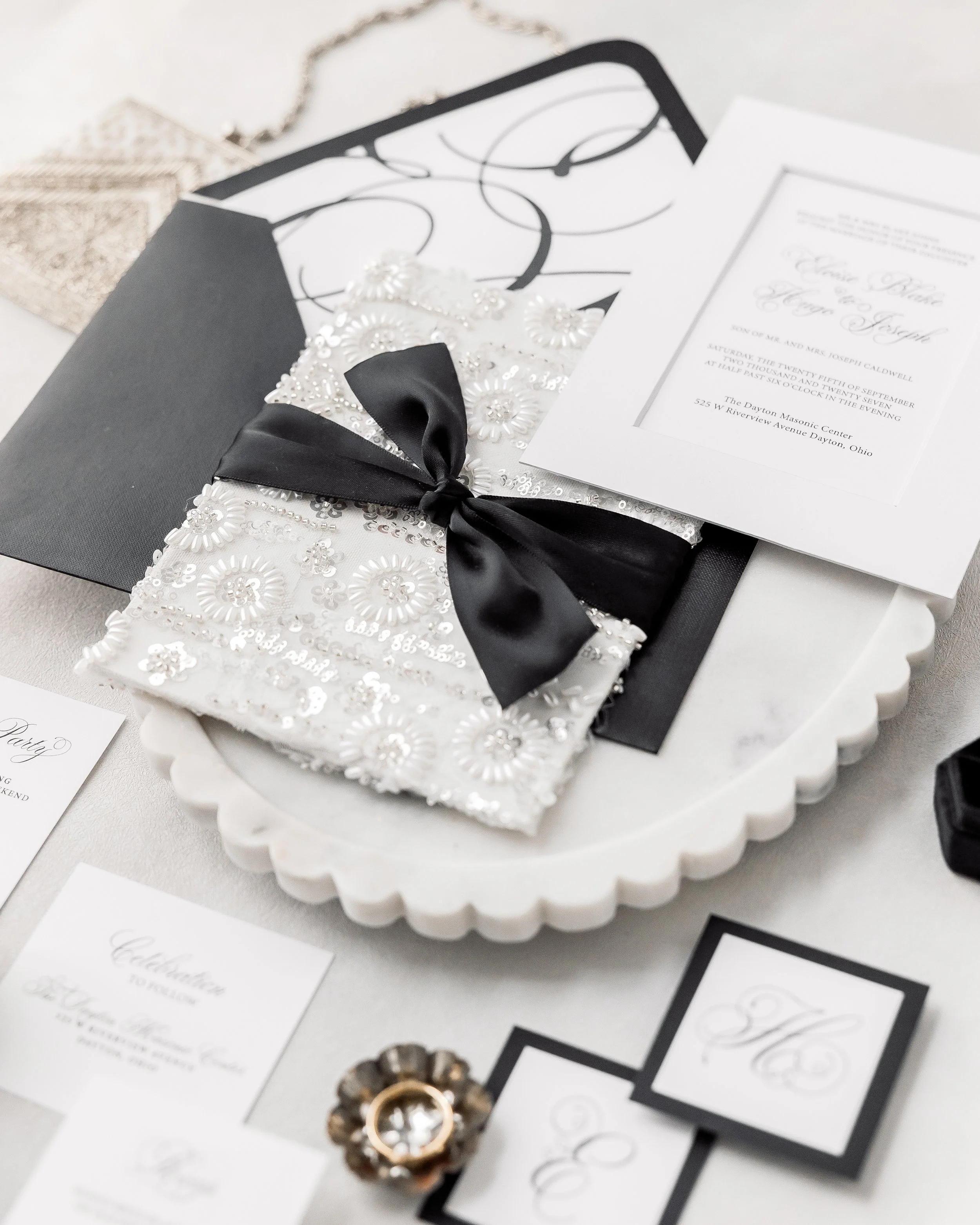 Pearls, metallics, sequins, and delicate silver highlights catch the light across the black-and-white palette, creating movement and depth that draws the eye across the suite.