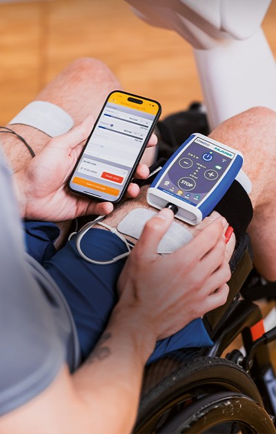 A person in a wheelchair holding a blood pressure monitor and a smartphone with a health app.