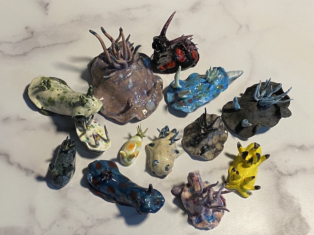 Collection of colorful glass animal sculptures resembling sea creatures and insects on a white surface.