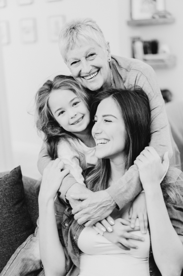 A joyful three-generation family embracing and smiling in a cozy home setting.