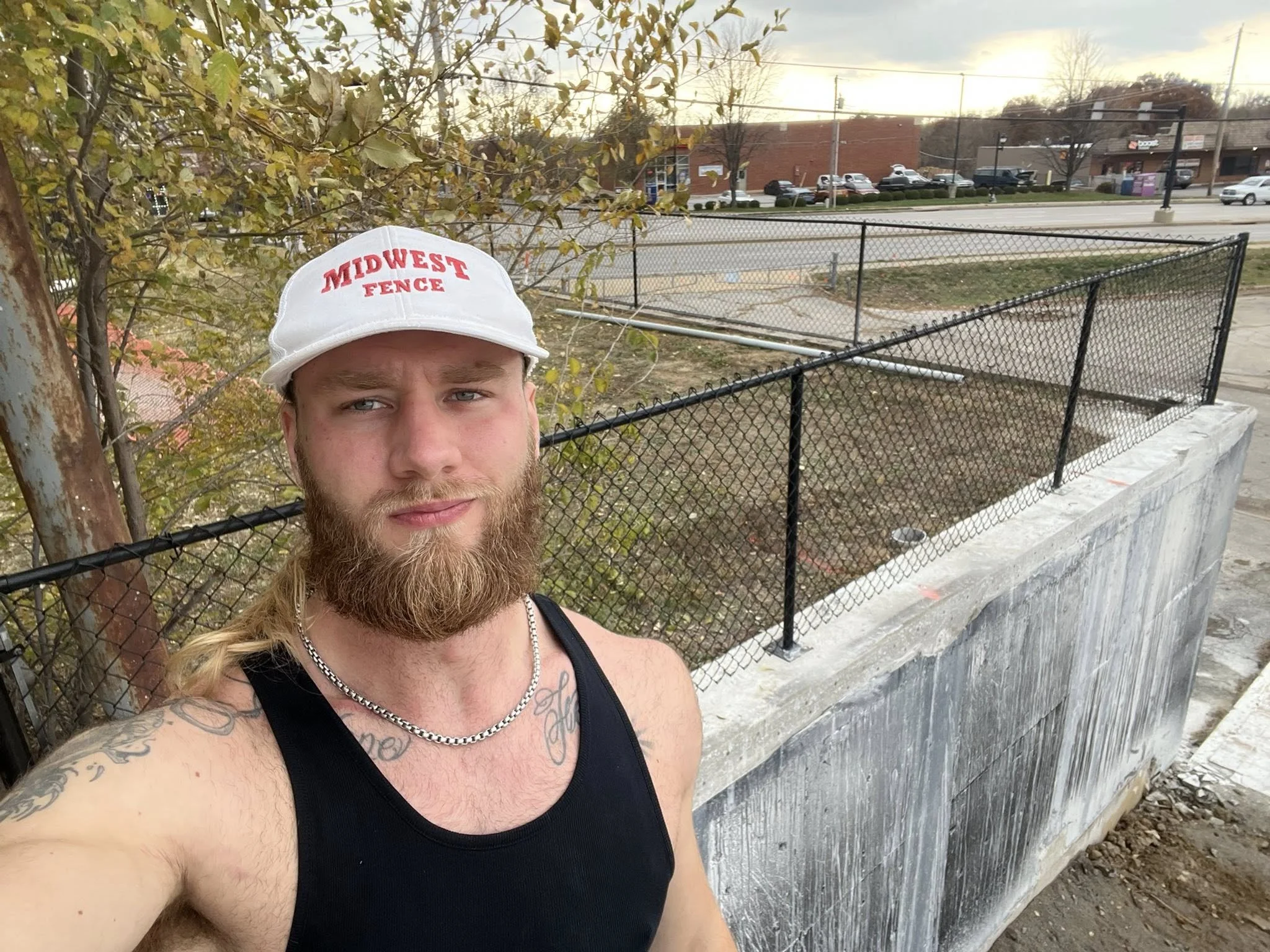 Midwest fence employee in front of black chain link fence