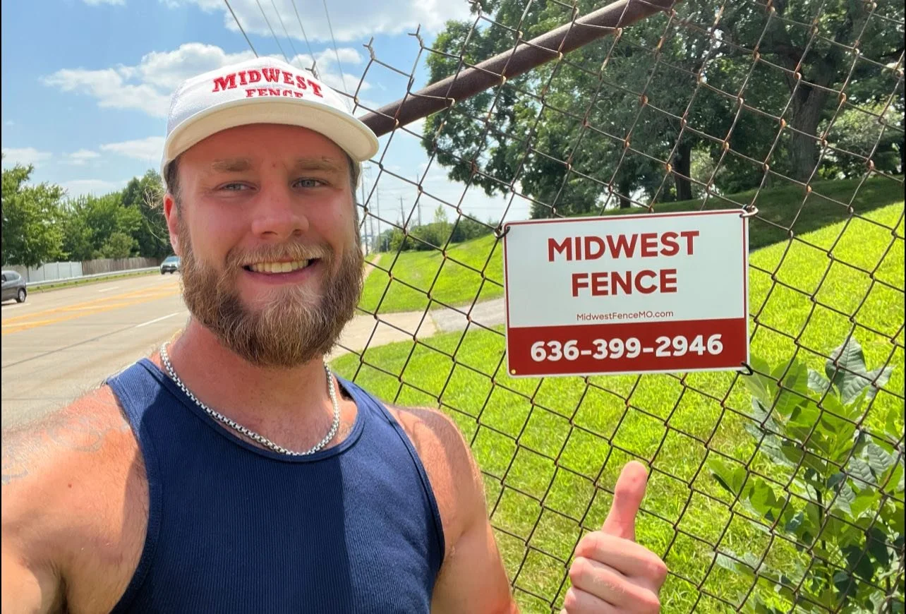 Midwest fence employee in front of chain link fence and Midwest Fence sign