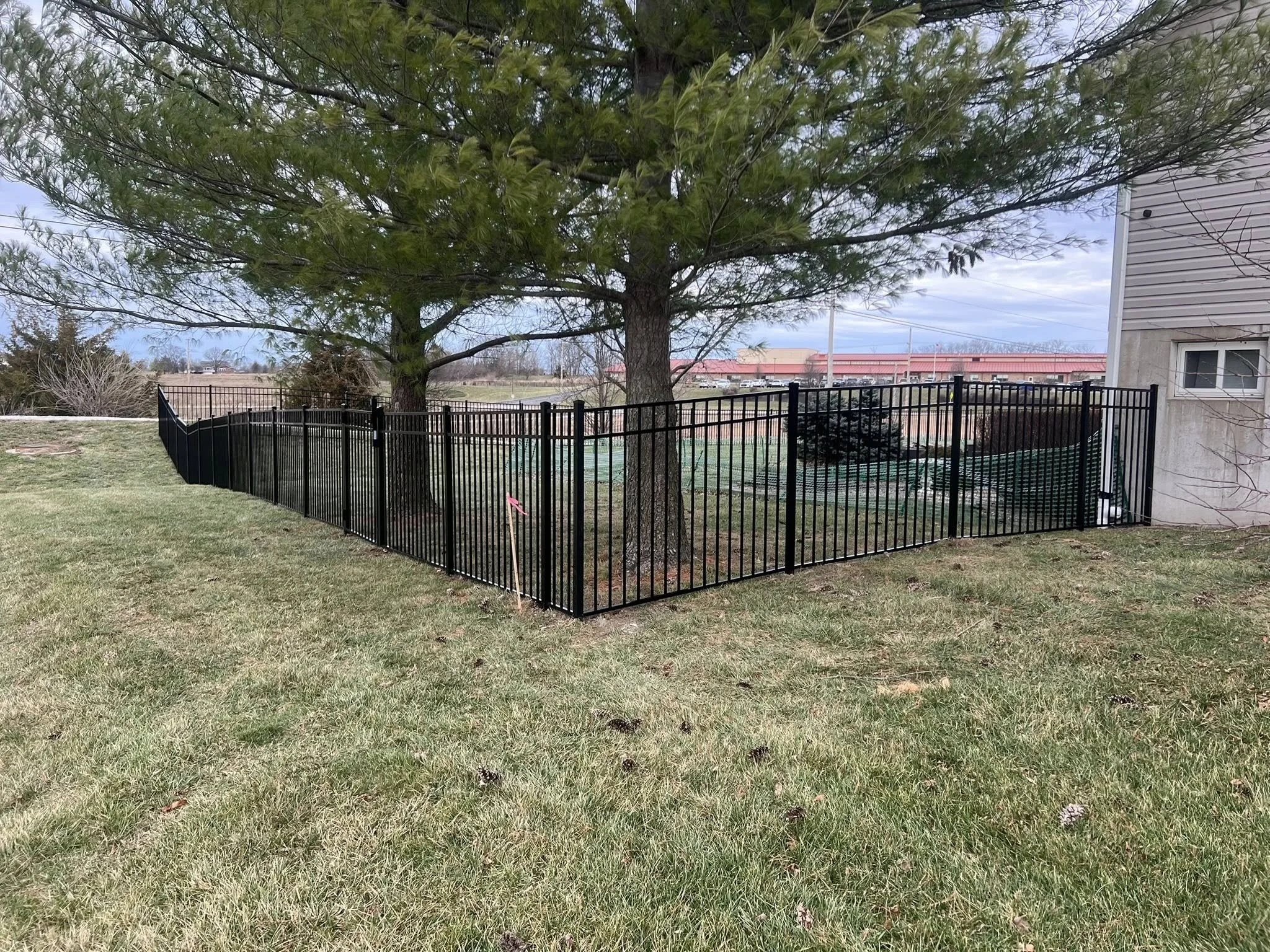 black ornamental aluminum fence in large backyard with hill