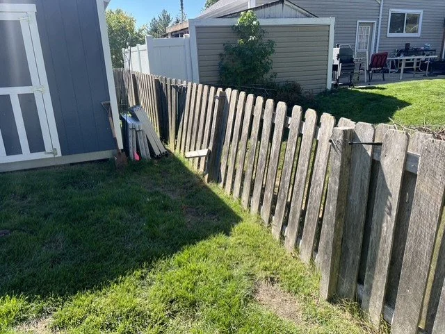 Leaning cedar picket fence with rotted wood posts in St. Charles County