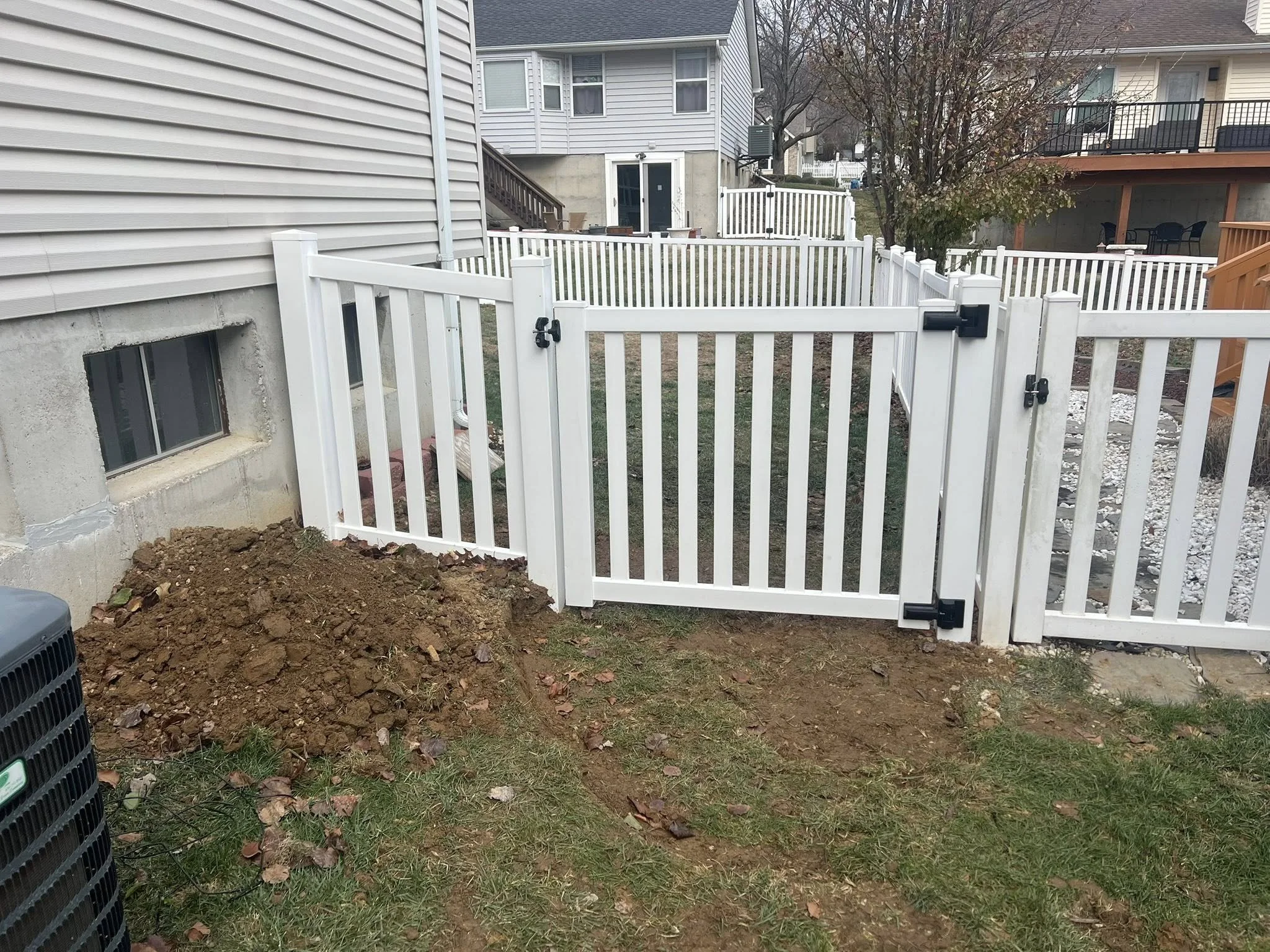 white semi-privacy vinyl fence with gate opening in backyard