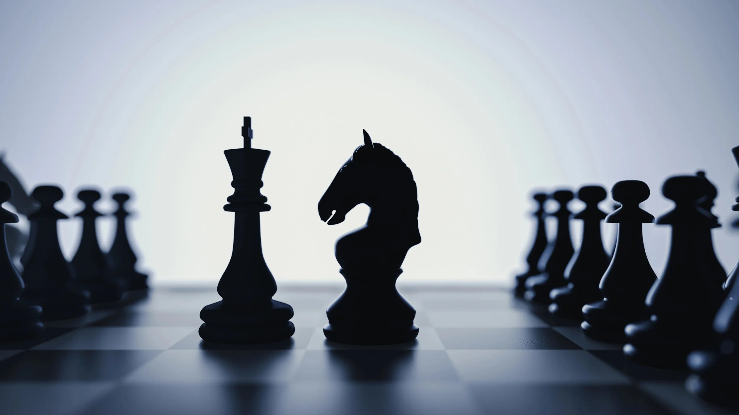 Silhouette of a chessboard with a king and knight in the center, surrounded by other chess pieces, with a bright light source behind creating a dramatic effect.