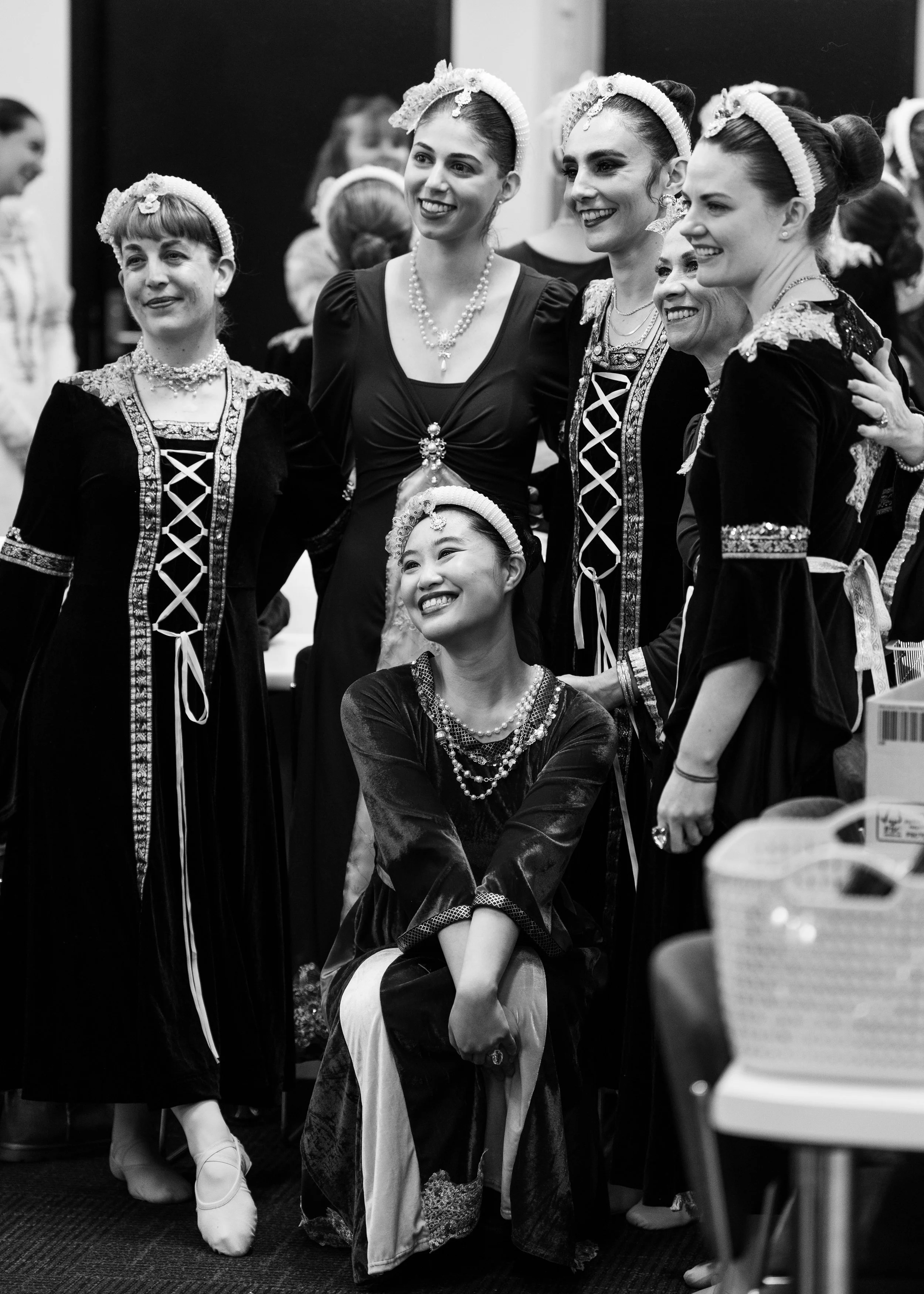 Adult Ballet Centre dancers dressed in Romeo and Juliet costumes, smiling and embracing each other in a backstage near dressing room setting.