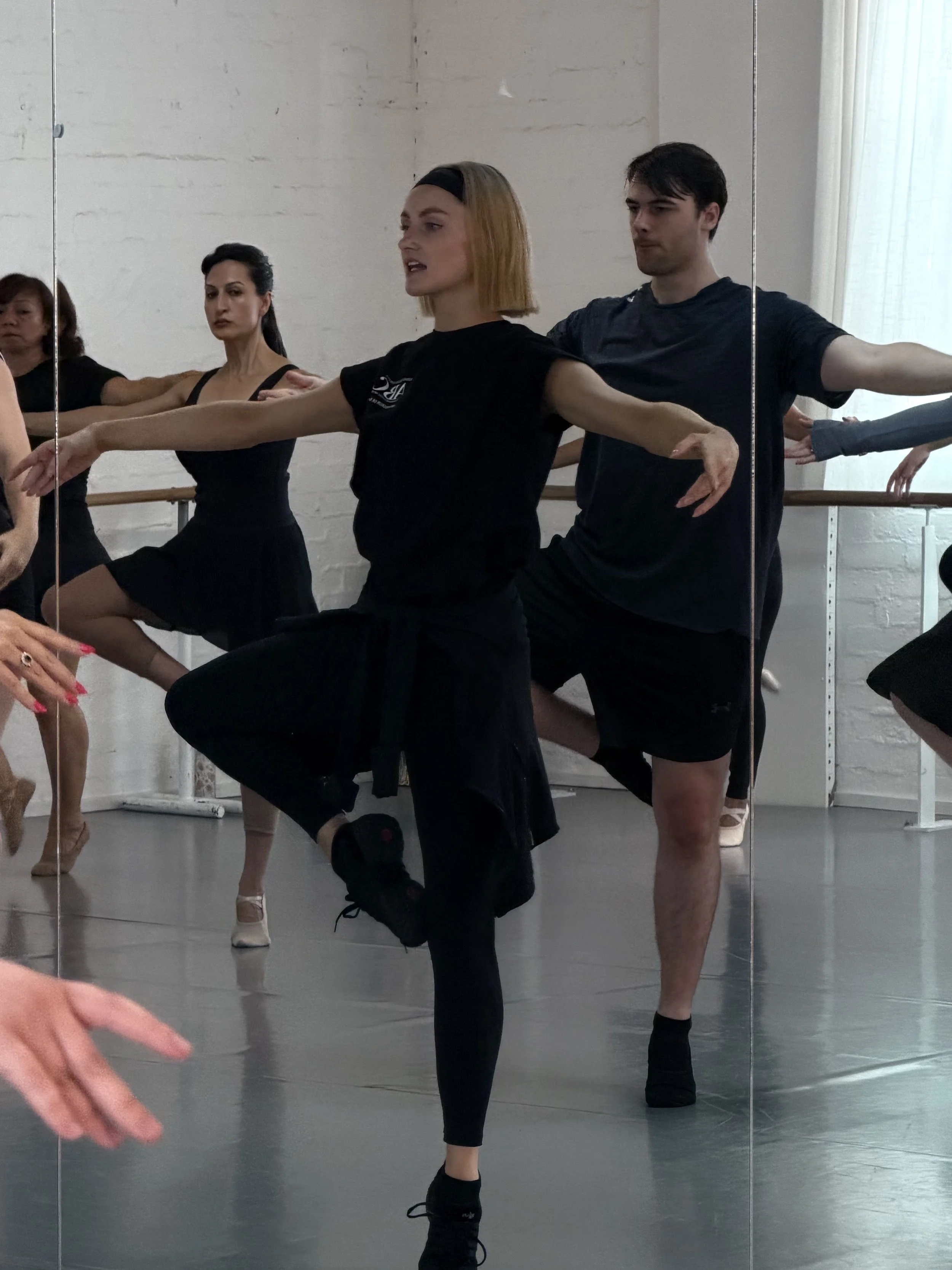 Group of ballet dancers practicing in a dance studio with mirrors.
