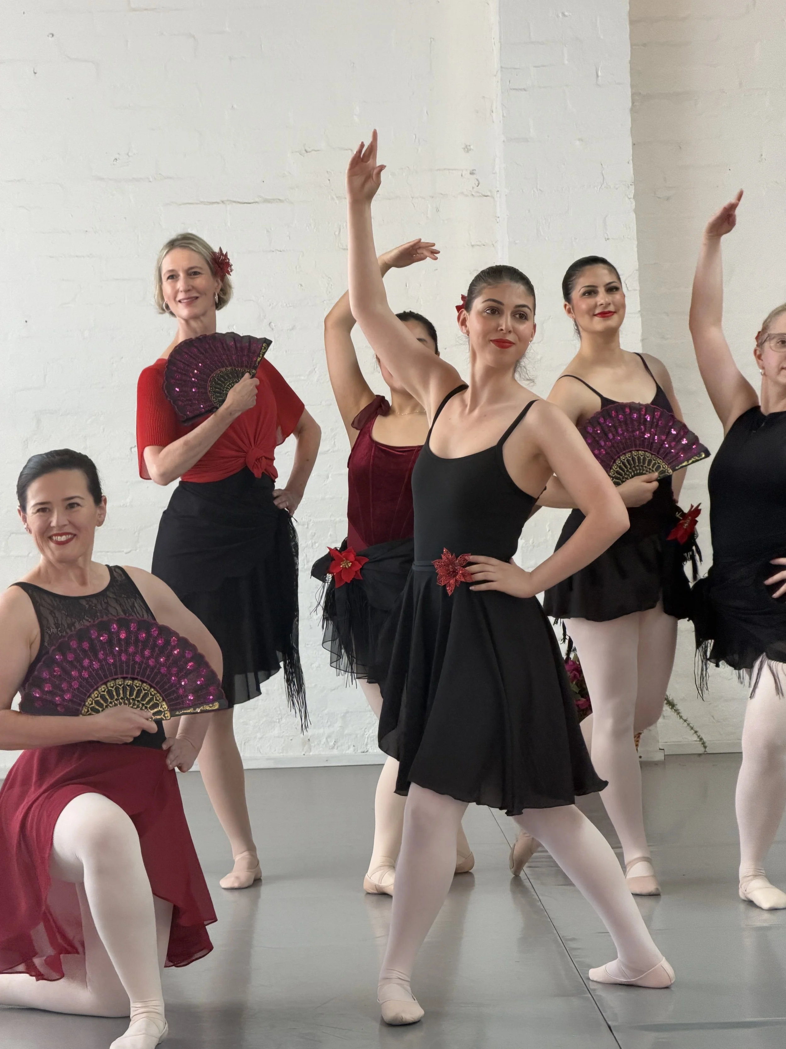 Ballet dancers in costumes practicing in a studio with white brick walls.