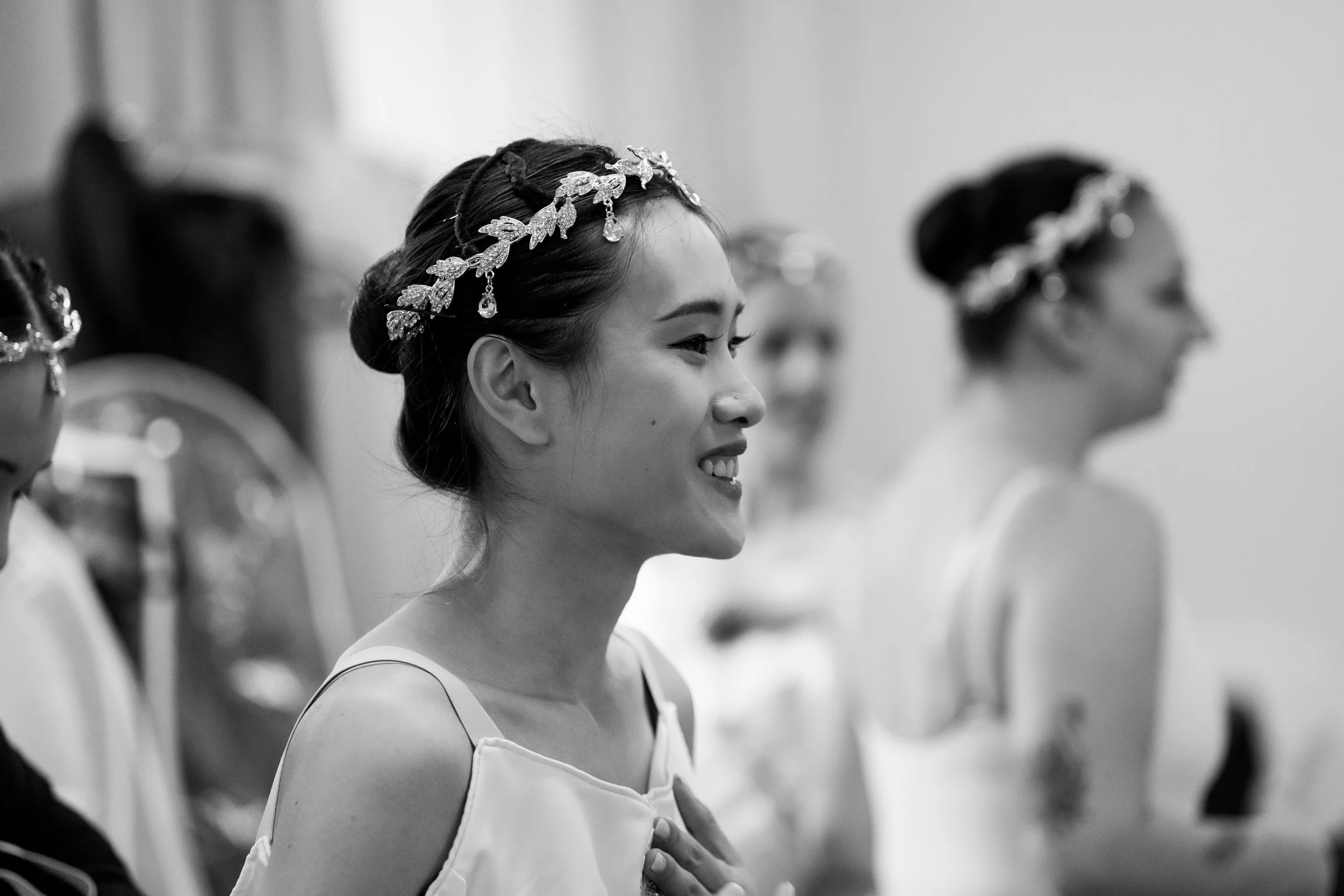 Black and white photo of women wearing decorative headpieces, dressed in ballet attire, likely during a rehearsal or performance.