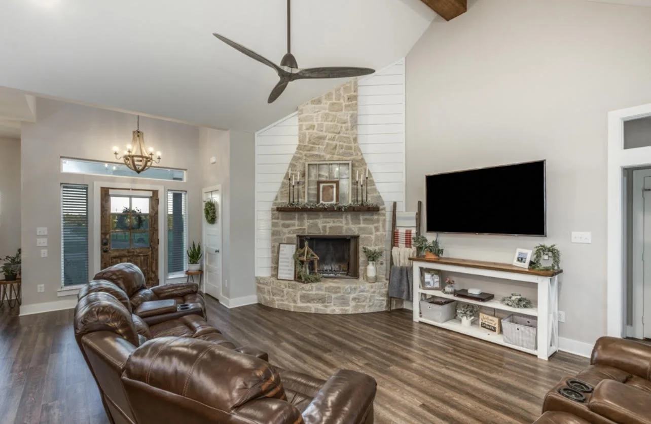 Custom home living room with vaulted ceiling, stone fireplace and wood flooring showing finish level choices