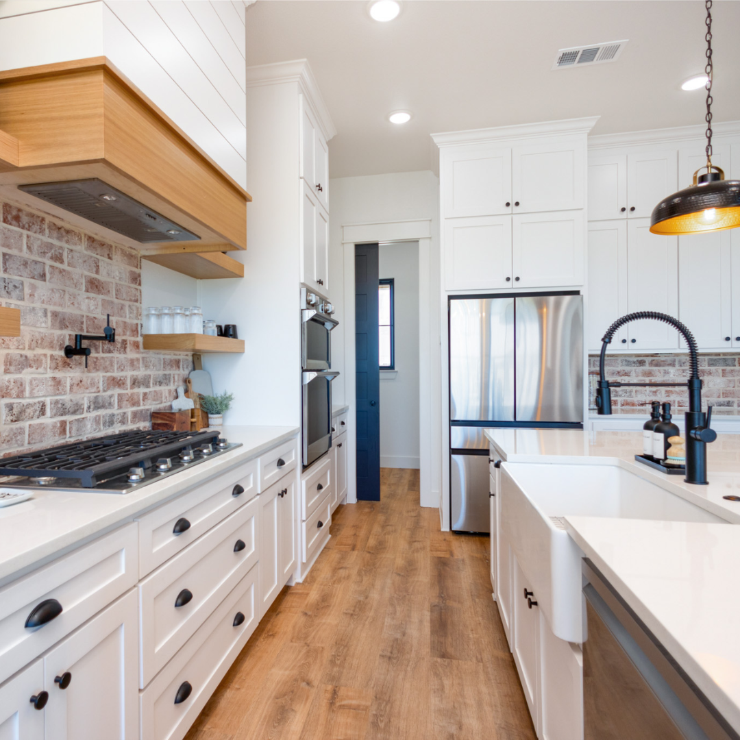 Modern kitchen with white cabinets, a brick backsplash, stainless steel appliances, and a wooden floor.