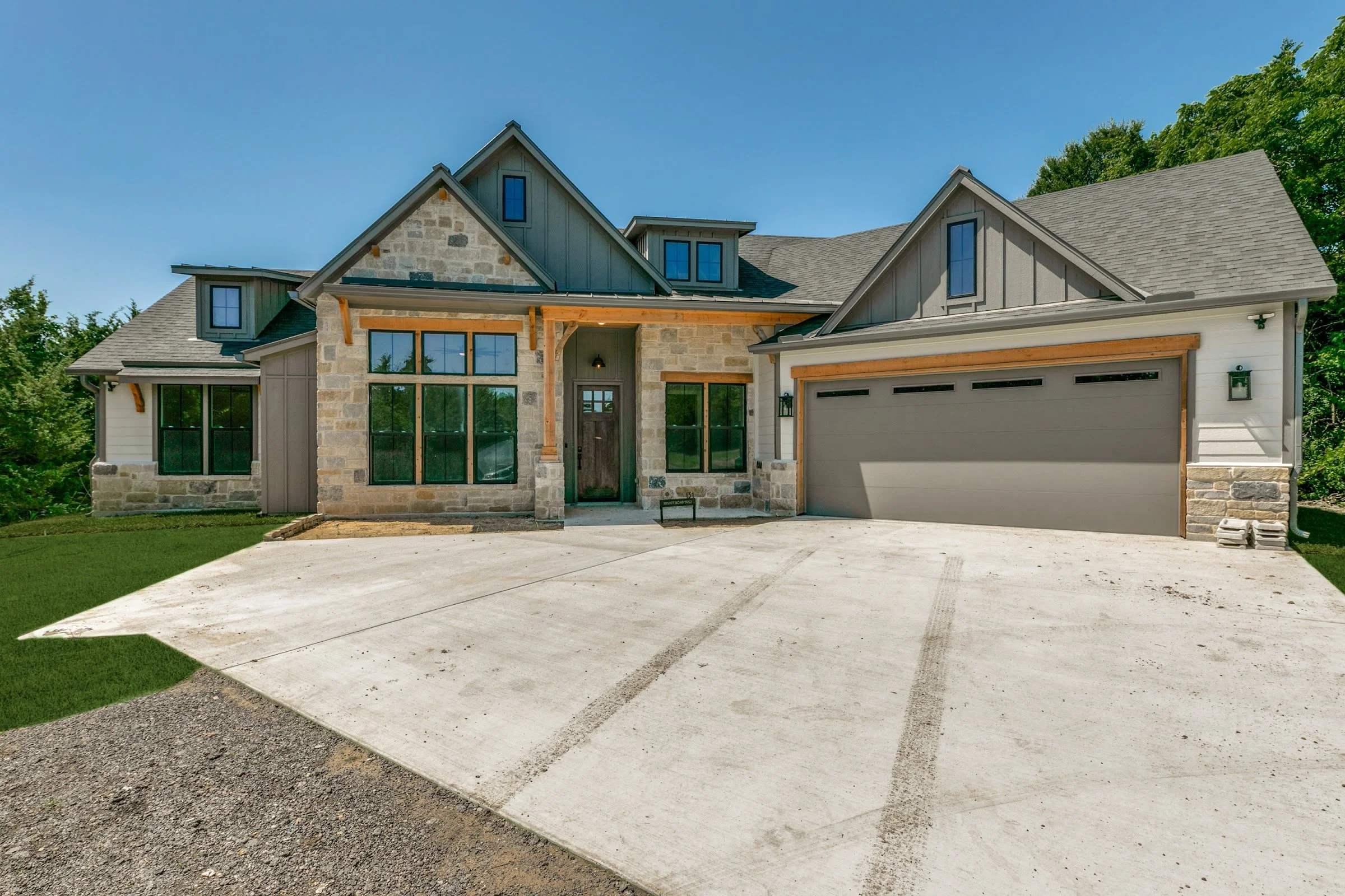 Completed North Texas custom home with stone and board-and-batten exterior and finished concrete drive