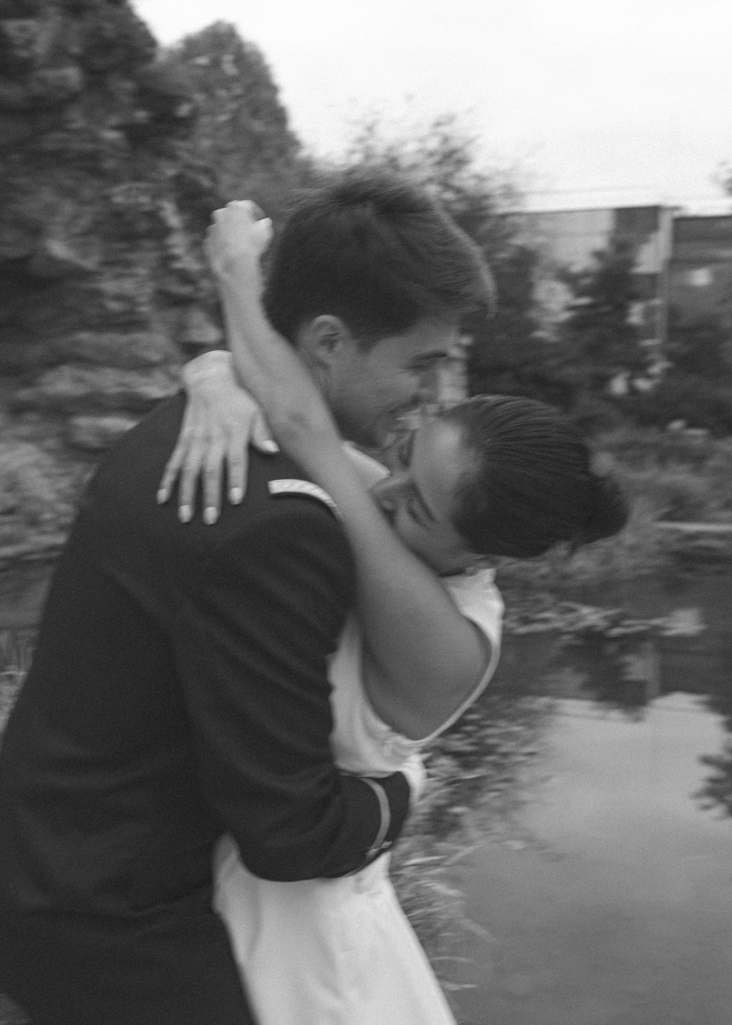 Deux personnes en train de s'étreindre près d'un plan d'eau, souriant et partageant un moment heureux.