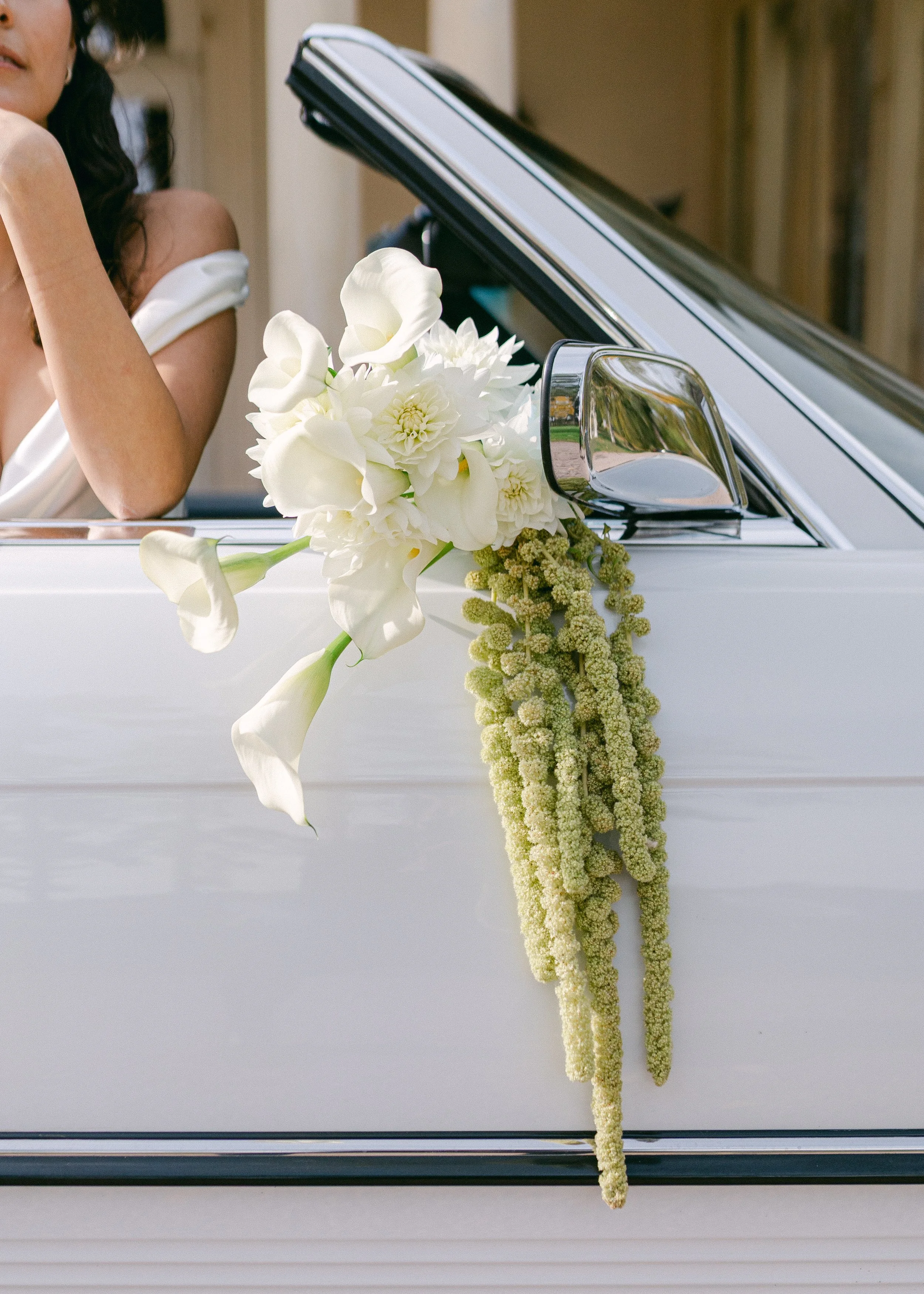 Une décoration florale blanche sur la portière d'une voiture blanche.