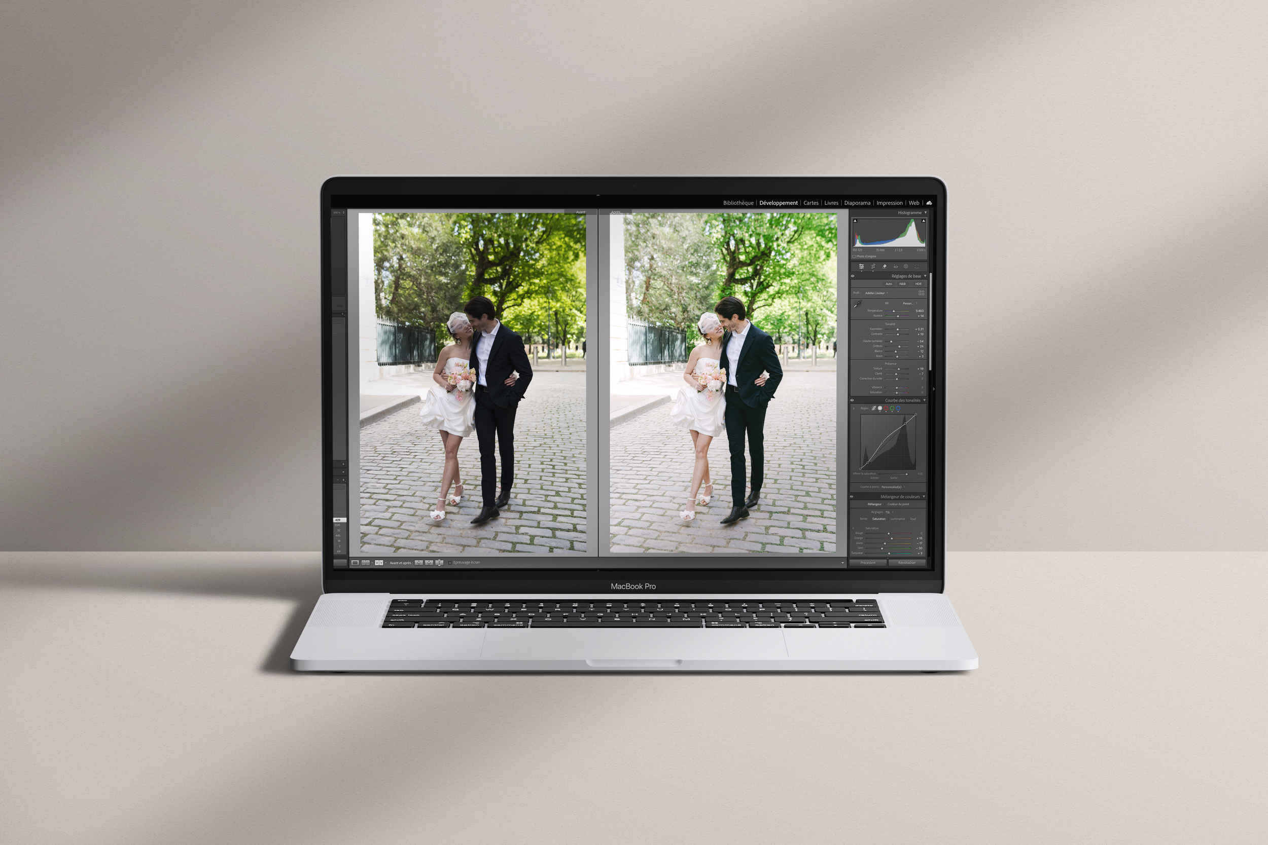 Un ordinateur portable MacBook Pro affichant une photo de mariage en cours de retouche avec un logiciel de photoédition. La photo montre un couple de mariés marchant sur une voie pavée, entourés d'arbres verts, avec le mec en costume noir et la fille en robe blanche.