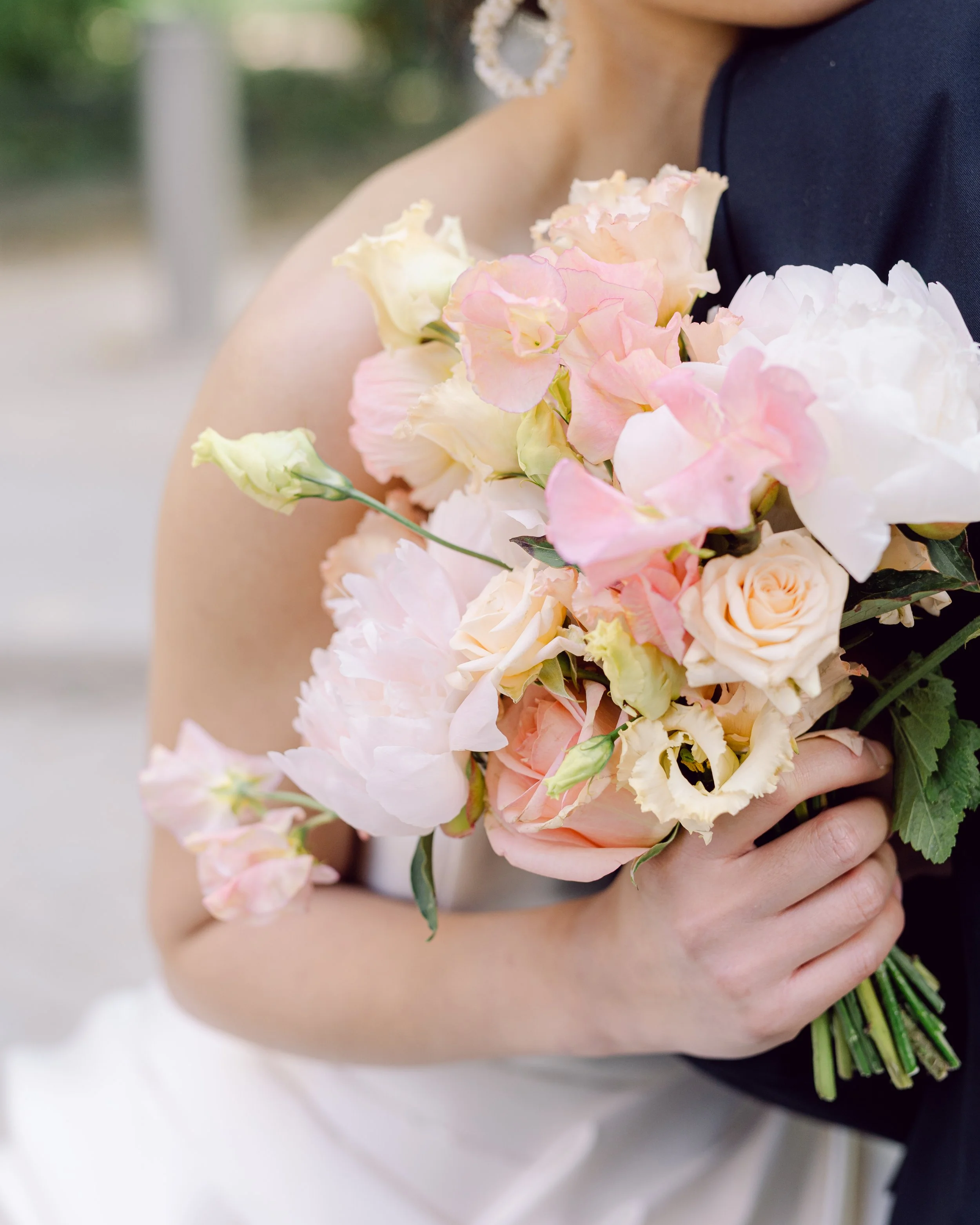 Une personne se tient avec une personne qui tient un bouquet de fleurs roses et blanches, lors d'une occasion spéciale.