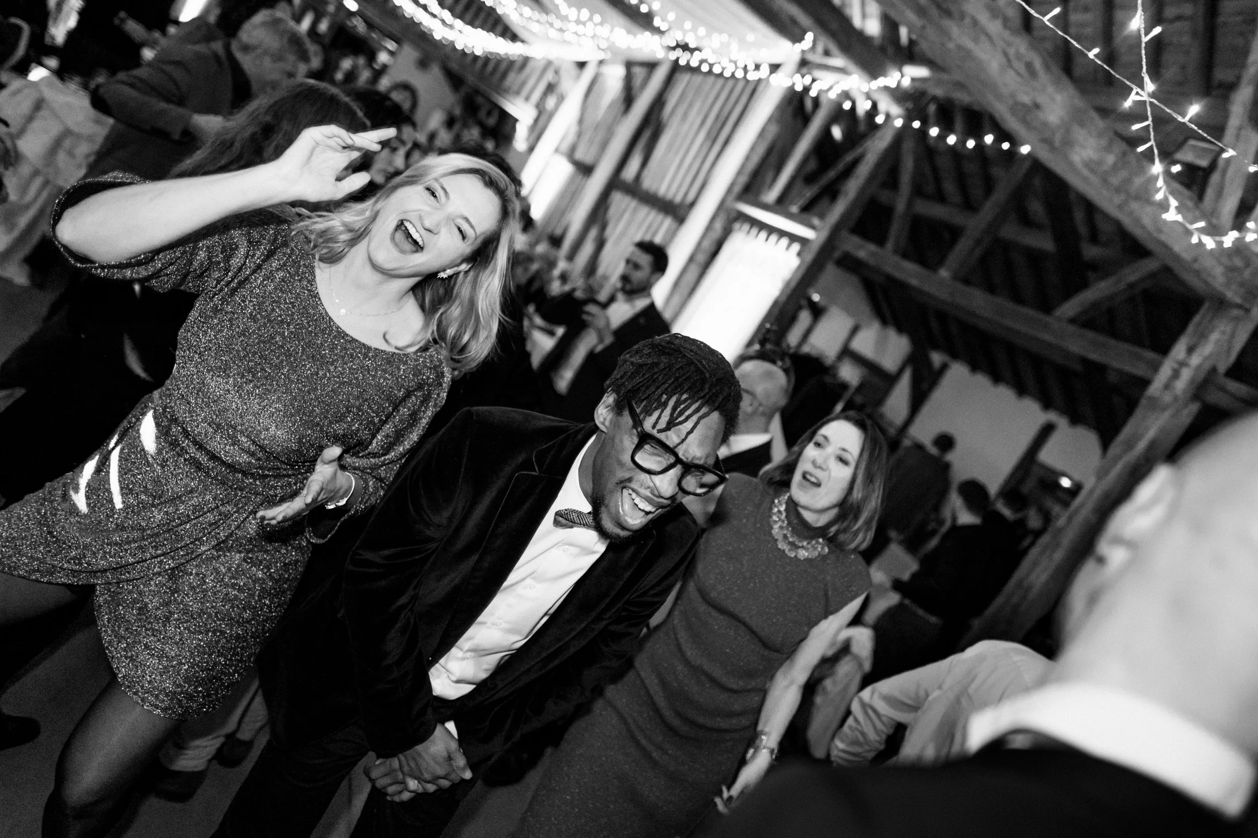 Groupe de personnes souriantes et dansant lors d'une fête dans une salle décorée avec des lumières