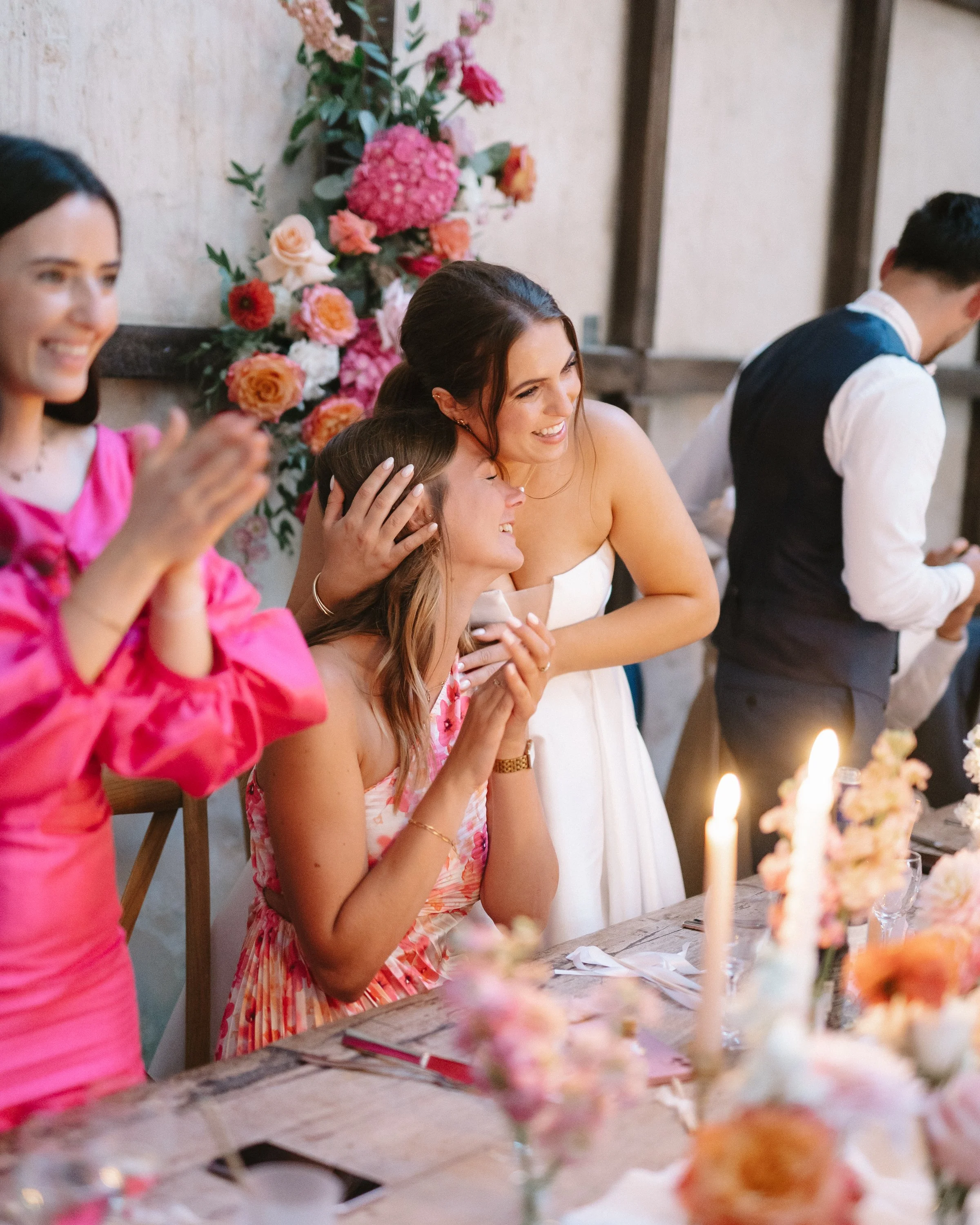 Groupe de femmes souriantes et émus lors d'une célébration avec décor floral et bougies.