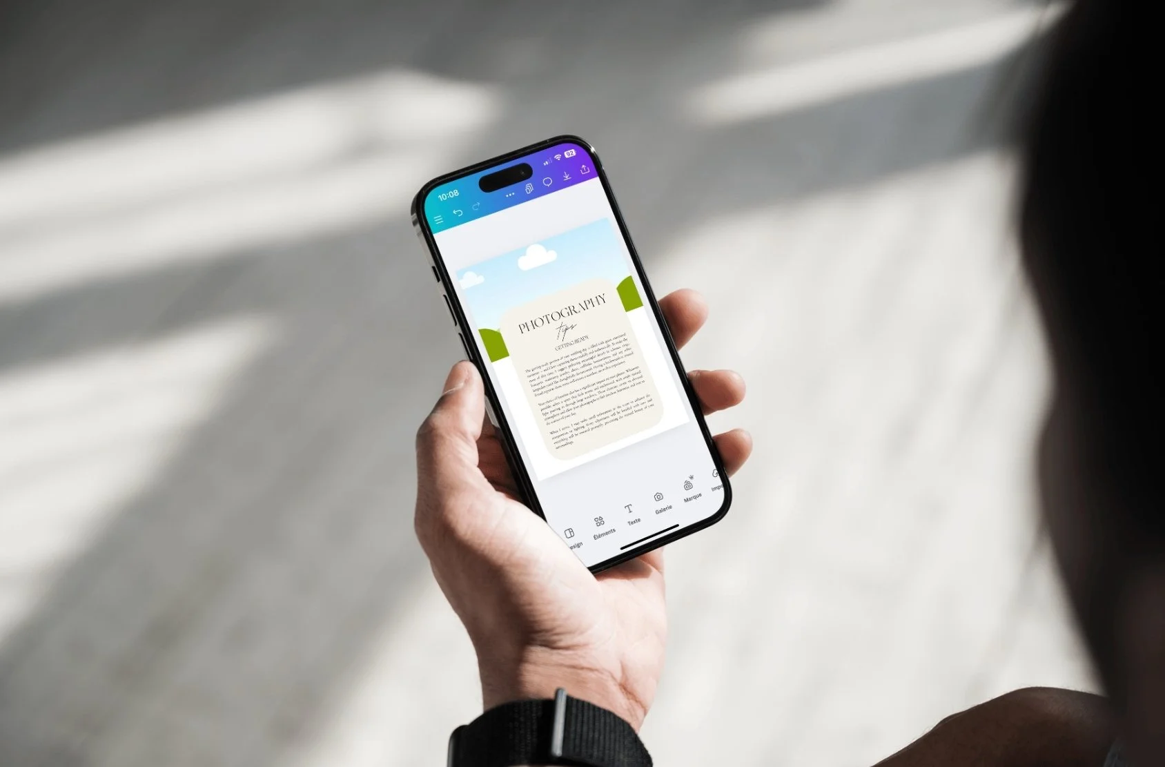 Une personne tient un téléphone portable affichant un document numérique avec le titre 'PHOTOGRAPHY' sur un fond naturel lumineux.