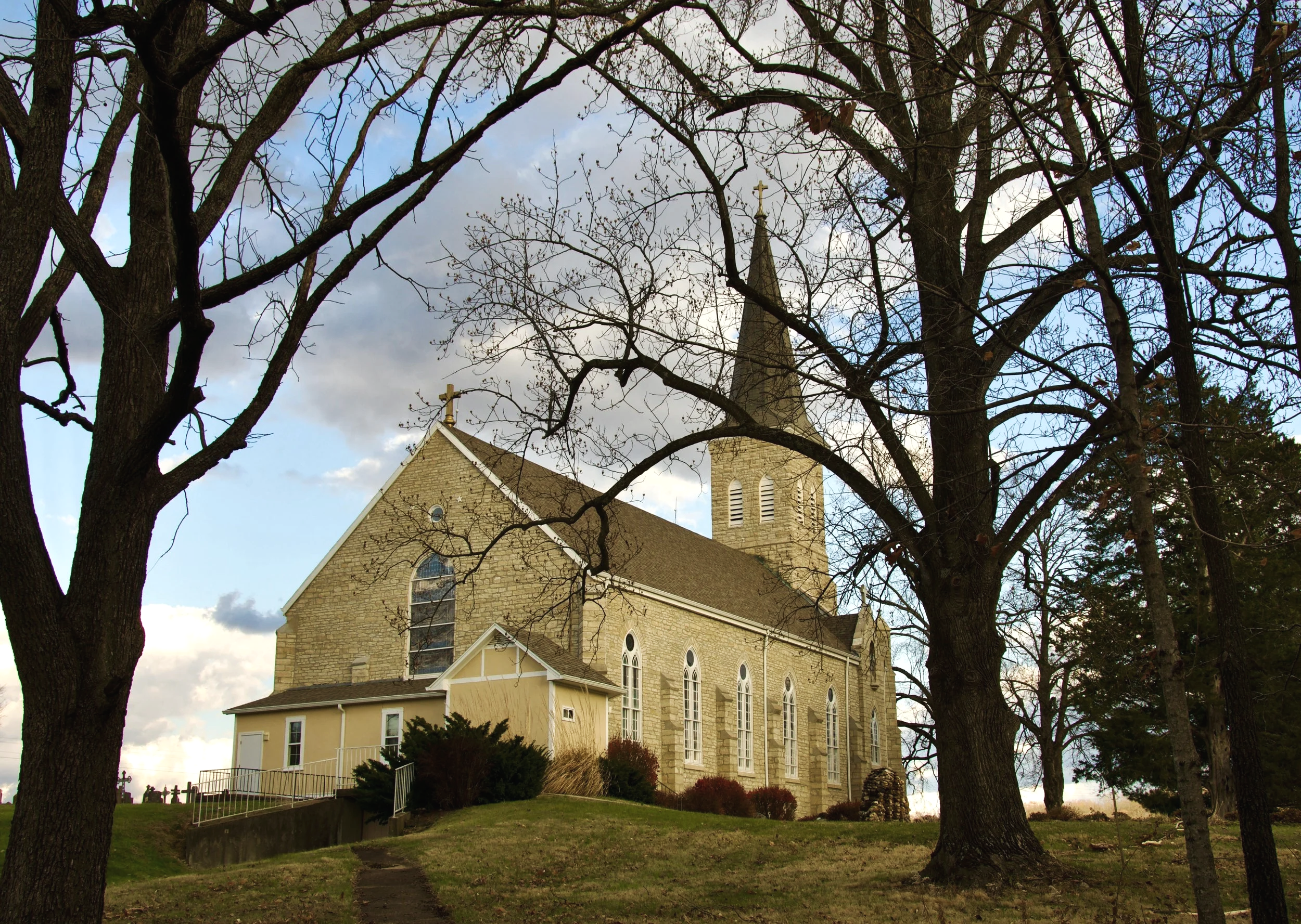 rural grey stone church with trees in the front