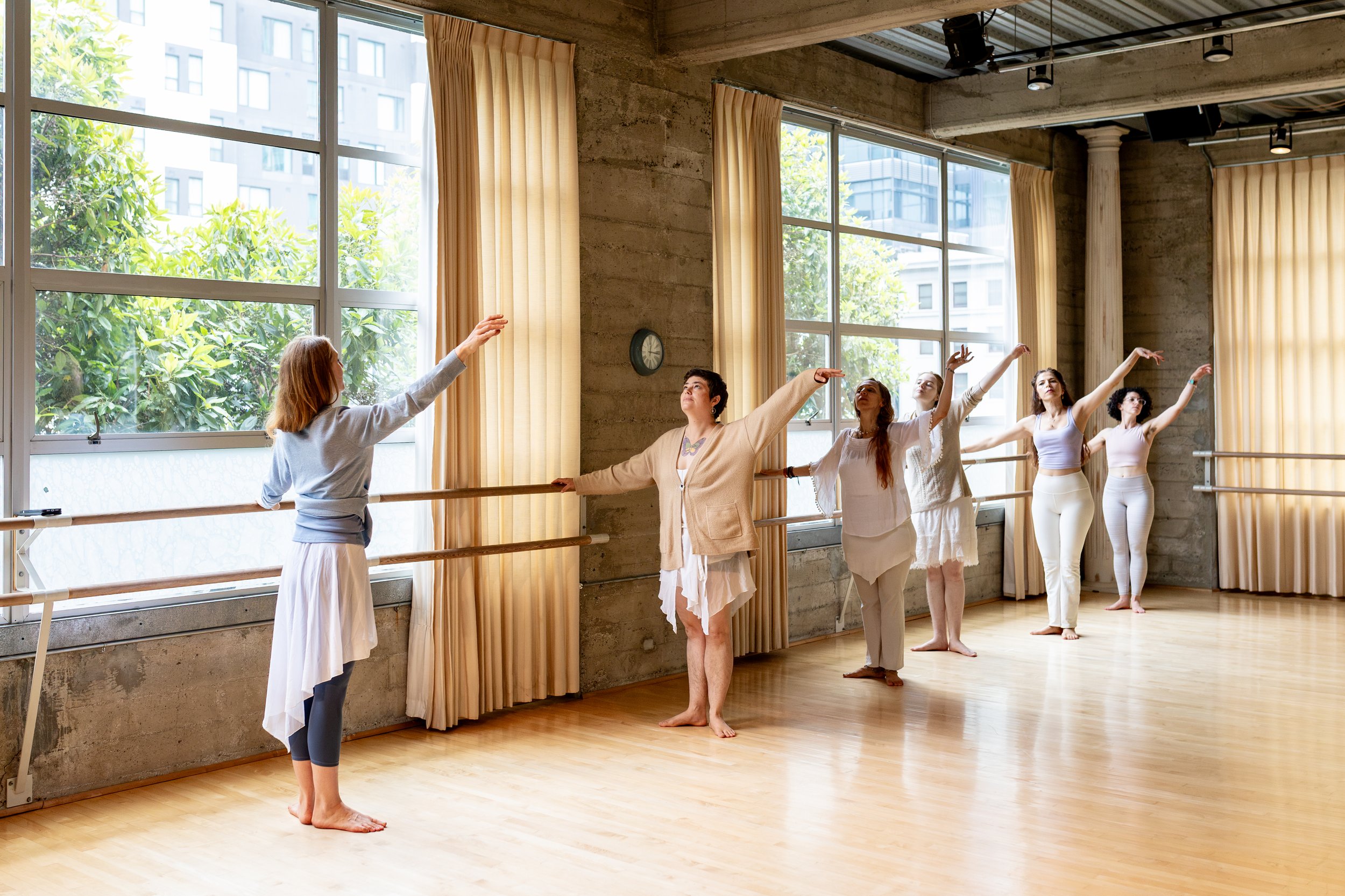 Ballet class practicing at the barre in a sunlit dance studio