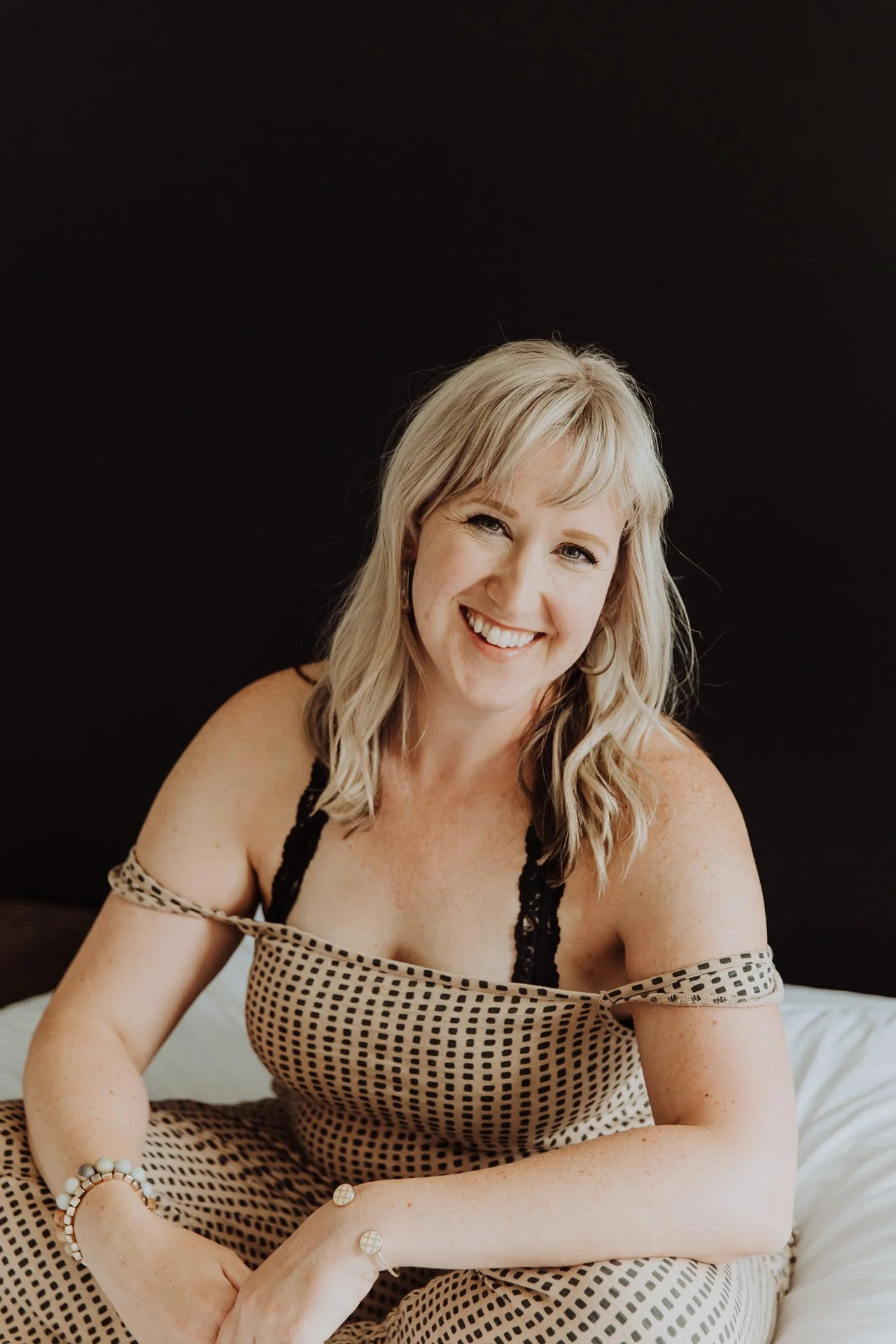 Janelle Kloske, OT and Sex Counselor, smiling at the camera, head tilted, black background