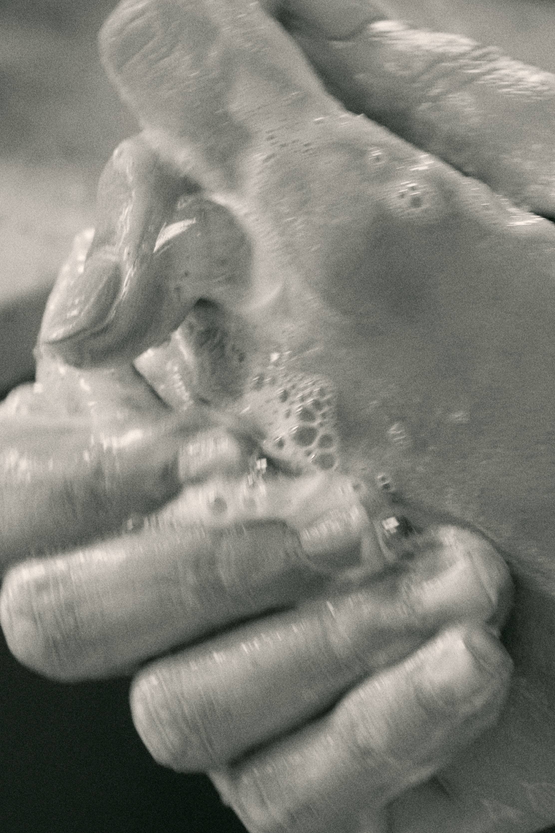Close-up of hands washing with soap, creating bubbles and lather in black and white