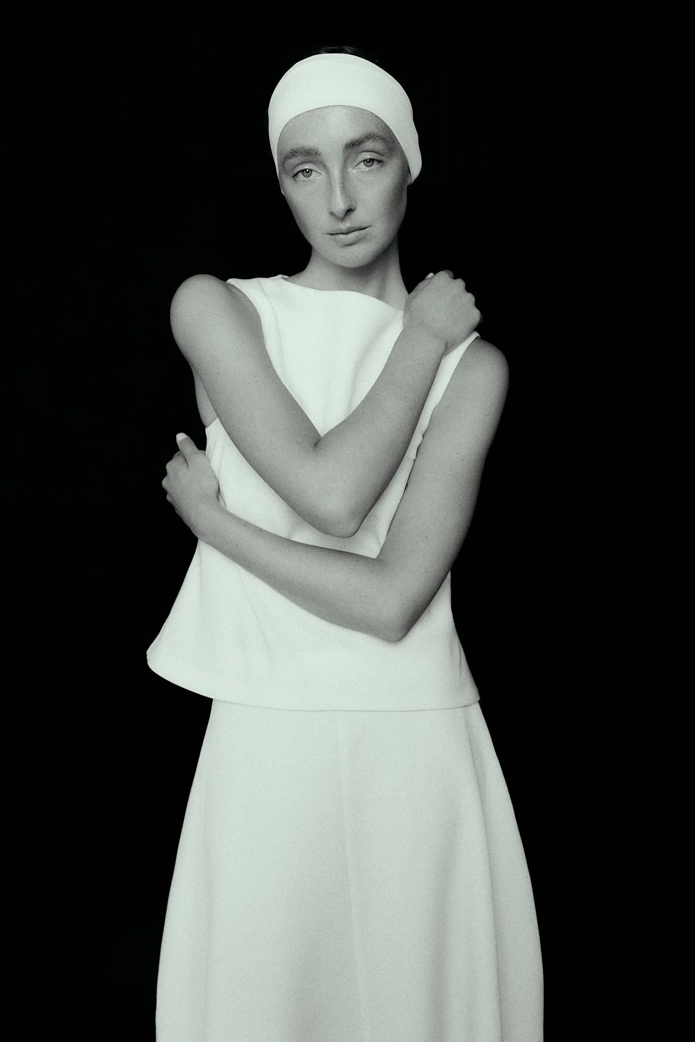 Woman in white standing with black background. Fashion
