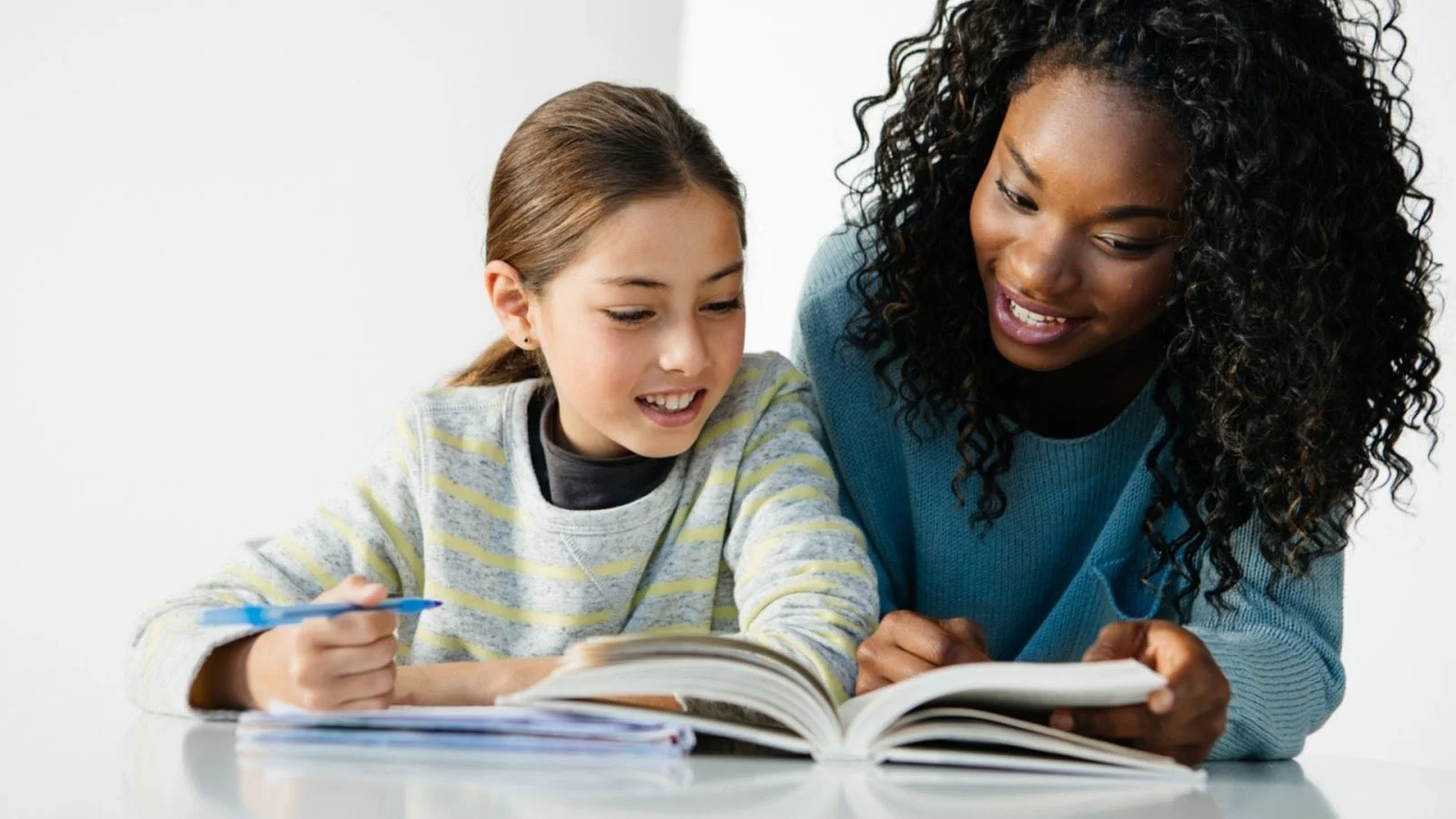 Une femme aide une jeune fille à étudier ensemble, en se concentrant sur un livre ouvert.