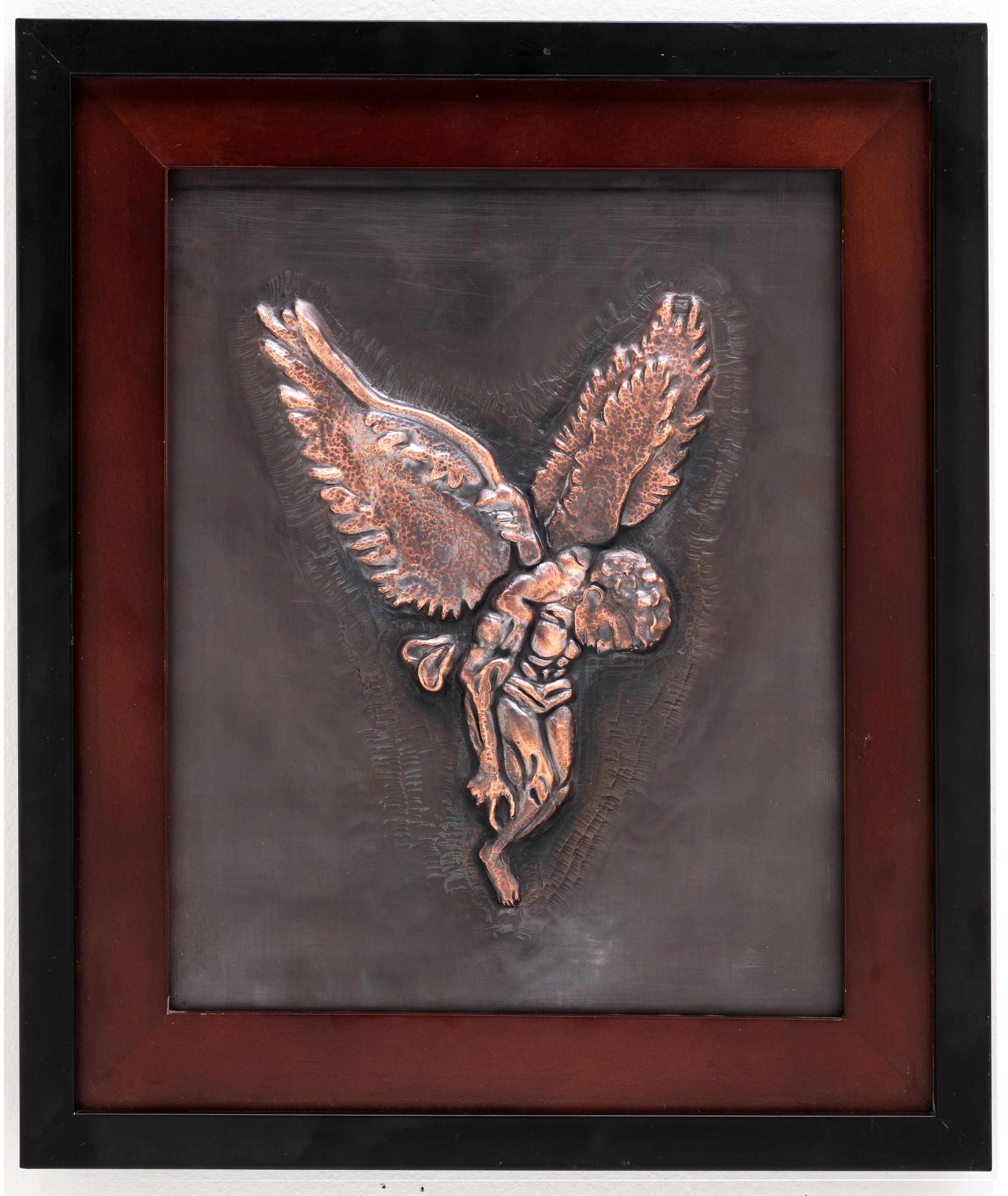Framed copper relief sculpture of icarus on a dark background