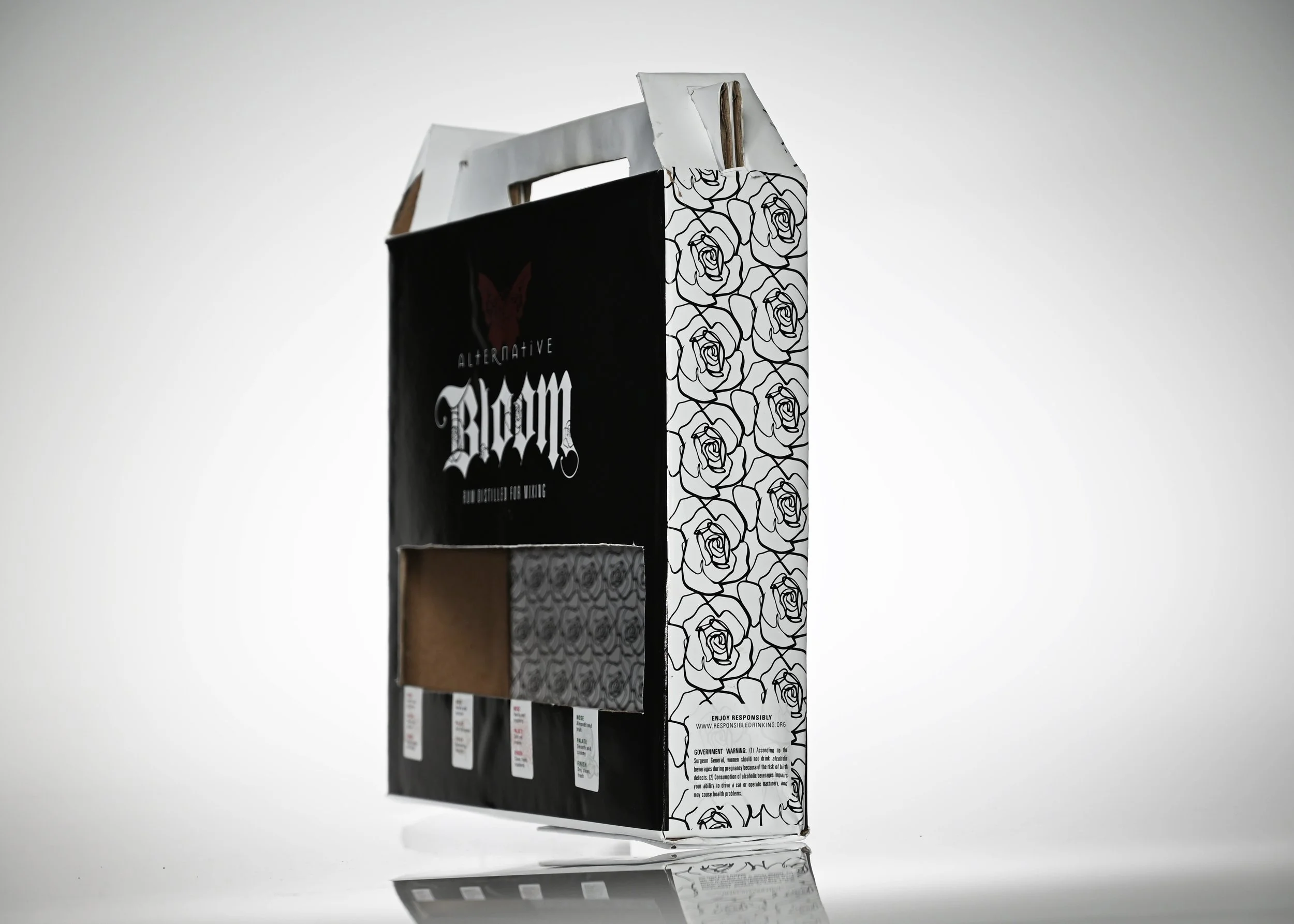 A cardboard pack of cigarettes with black and white floral graphics and warning labels.