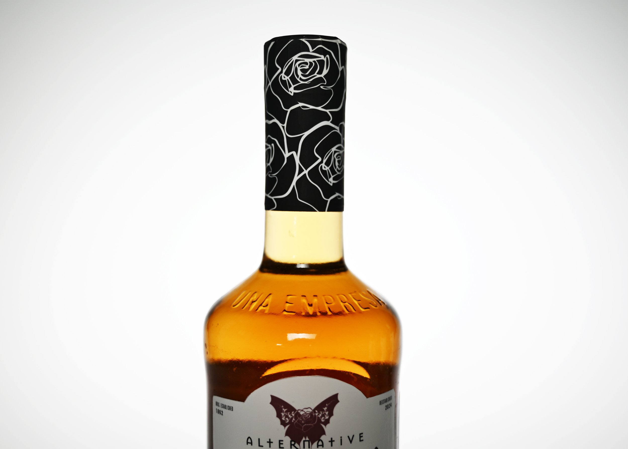 Close-up of a bottle with a black and white floral patterned cap and a partially visible label with a bat logo and the text 'ALTER UINTIVE' against a plain white background.