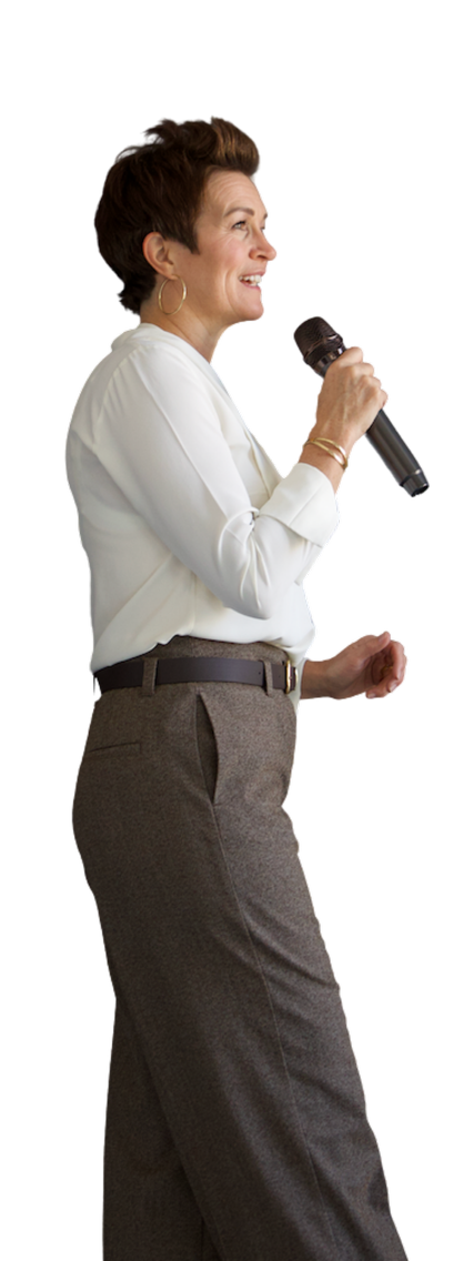 A woman with short brown hair holding a microphone, smiling and speaking.