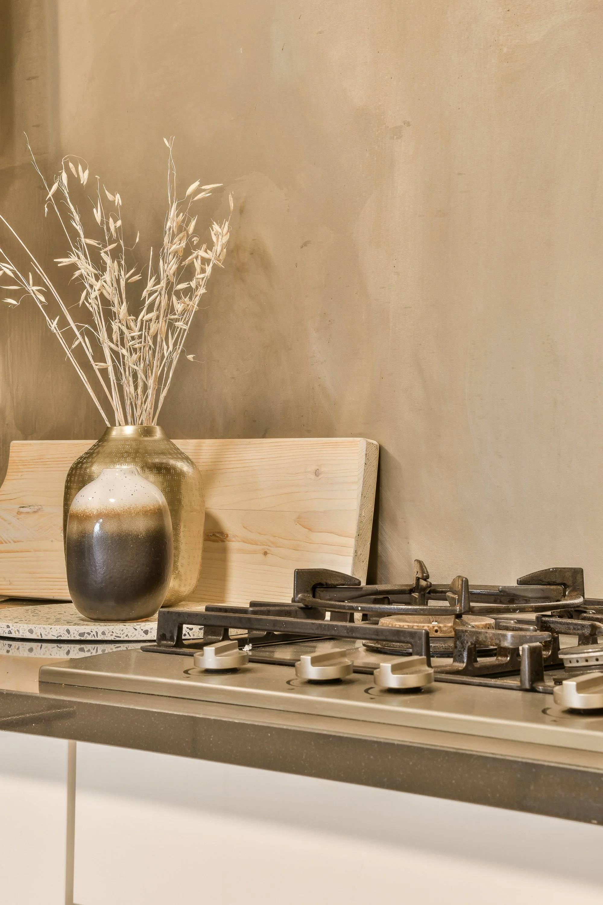 Stove top with metallic vase holding rye