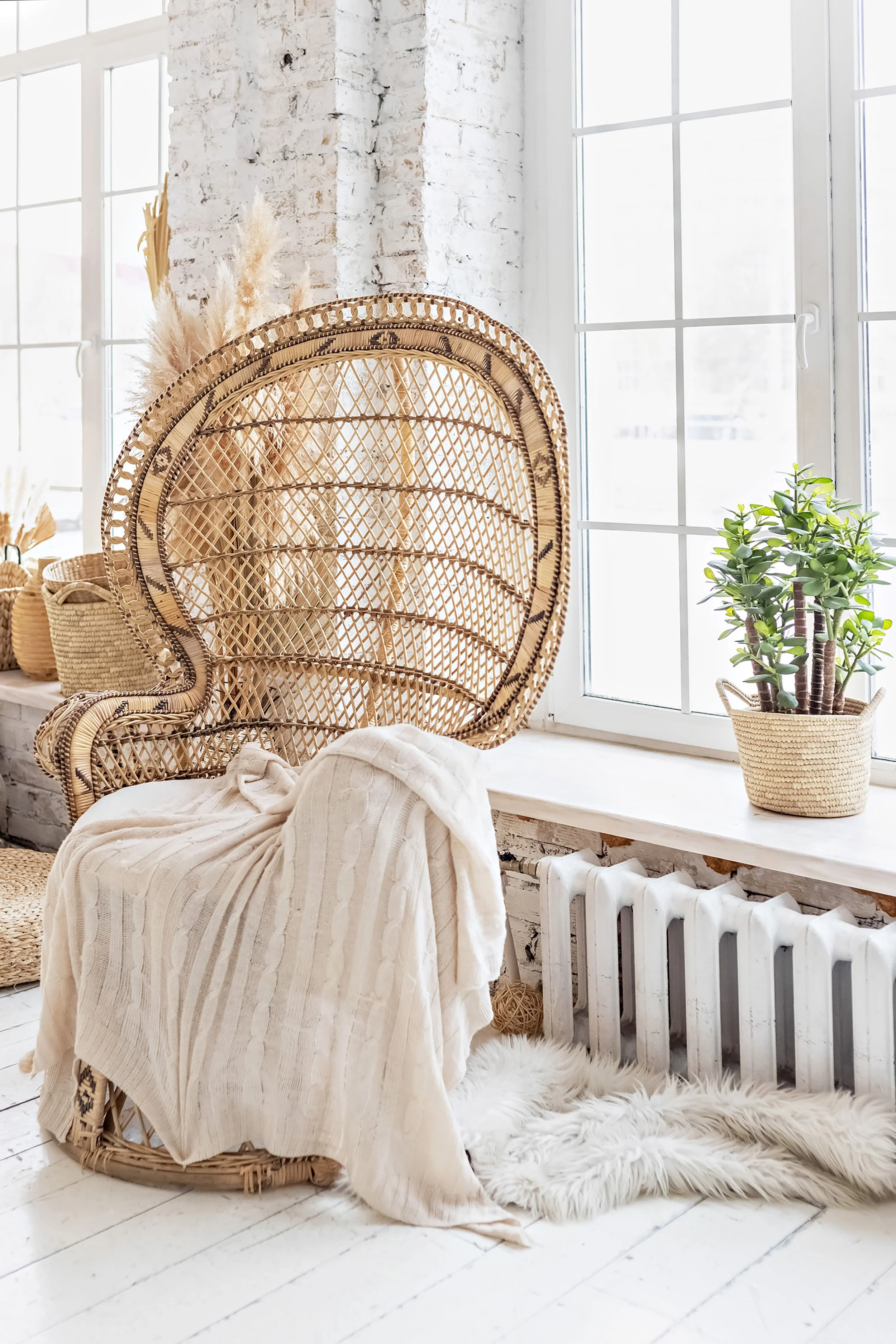 Soft neutral colors. A wicker chair holding a blanket with wheat and wicker behind.