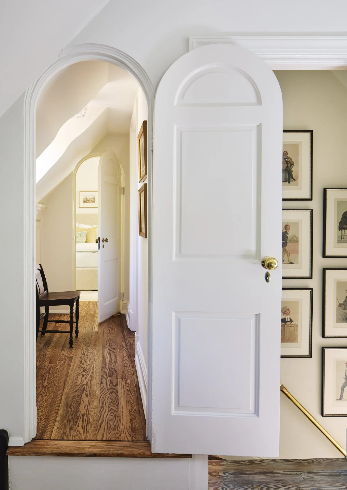 Interior view of a home with white walls, wooden floor, open doorway, and framed artwork on the wall.