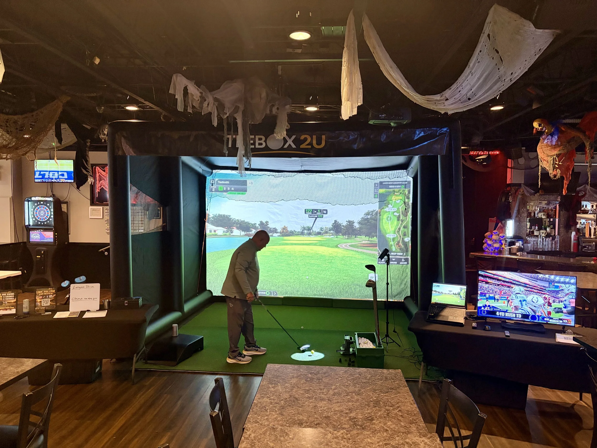 Golfer using a TeeBox2U indoor golf simulator with a projected virtual course at an event.