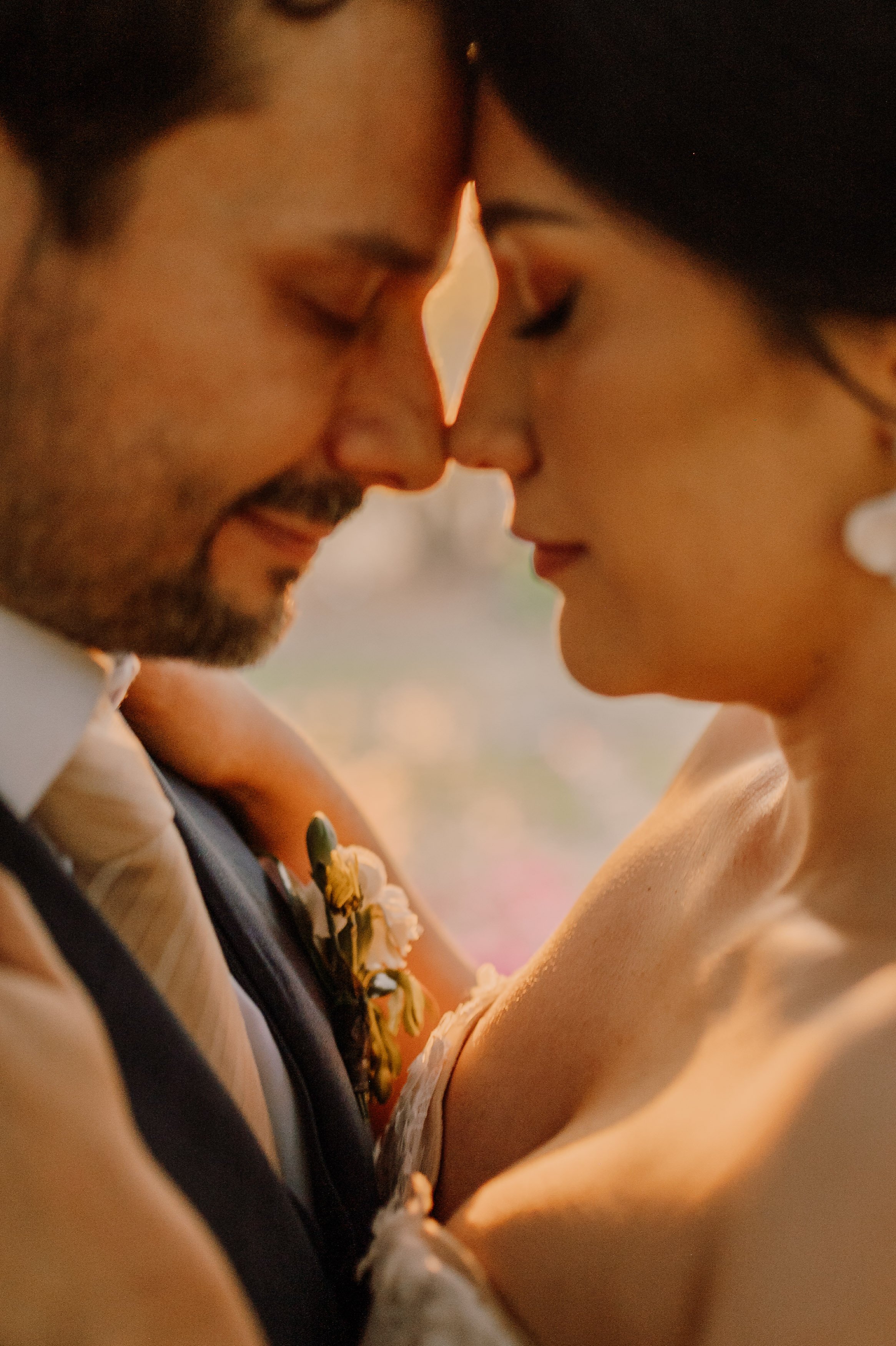 Pareja de novios en un momento íntimo, tocándose con la frente y los ojos cerrados, en una boda.