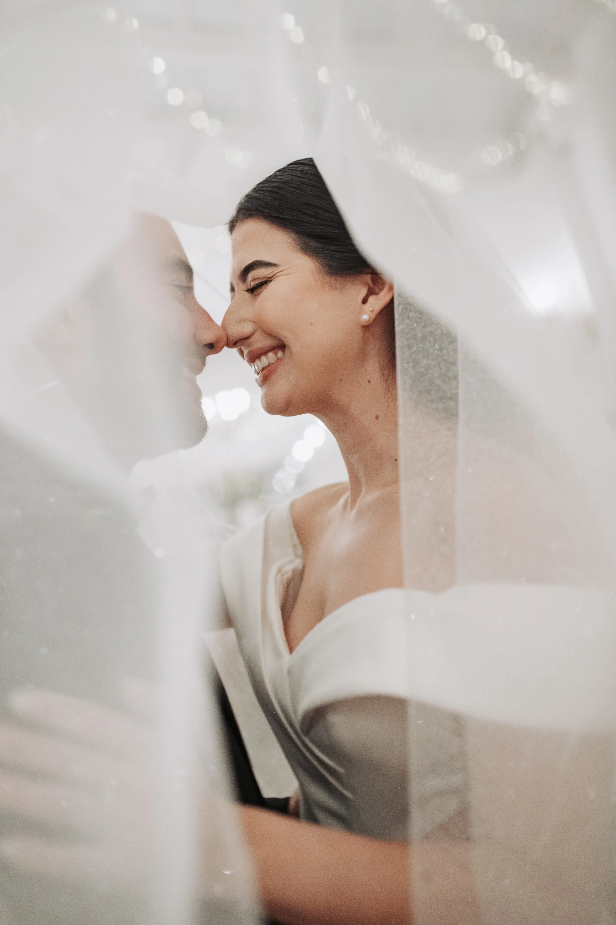 Una pareja sonriendo y tocándose la cara con ojos cerrados, en un enfoque cercano y romántico.